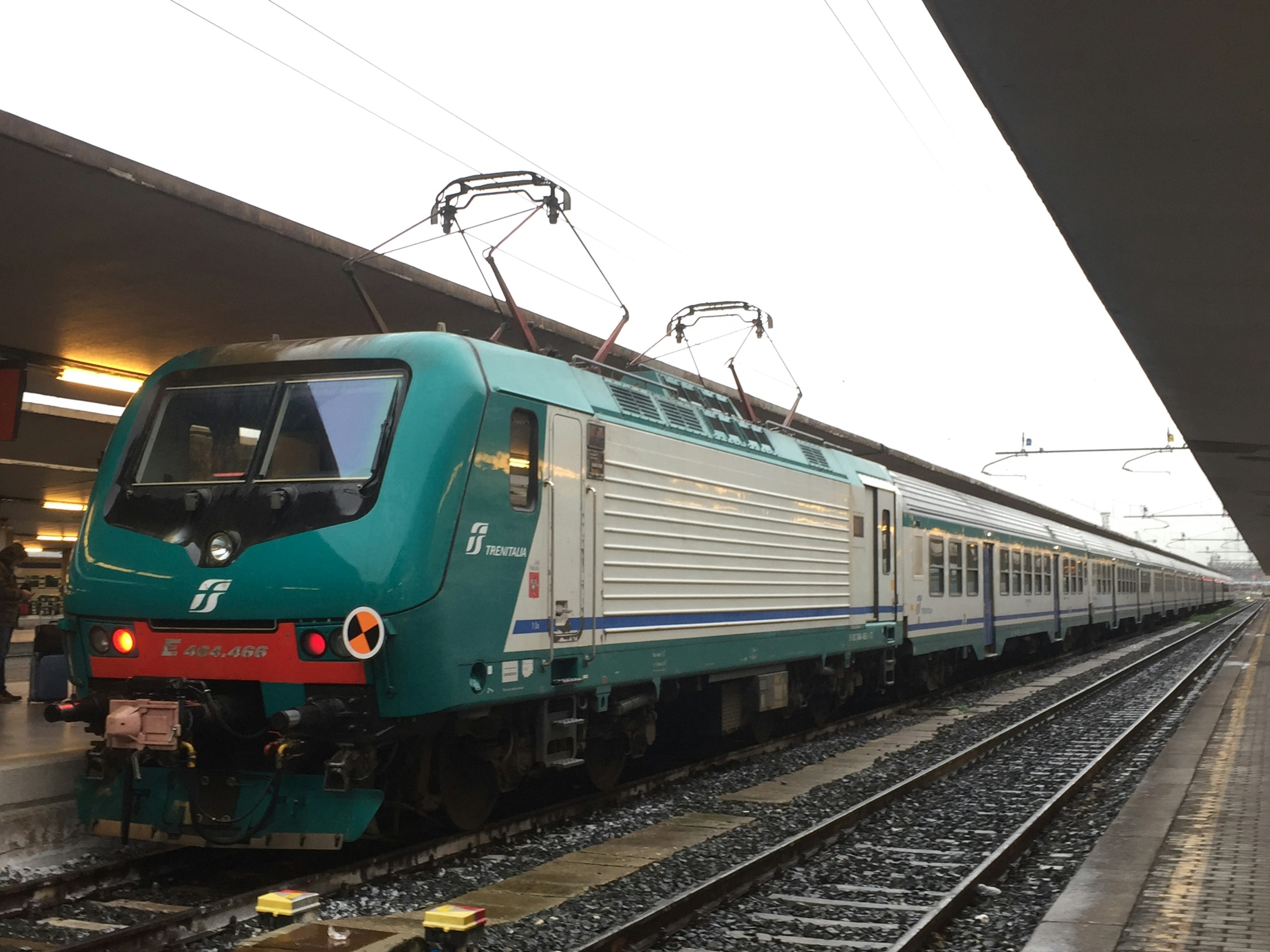 A green train stopped at a train station