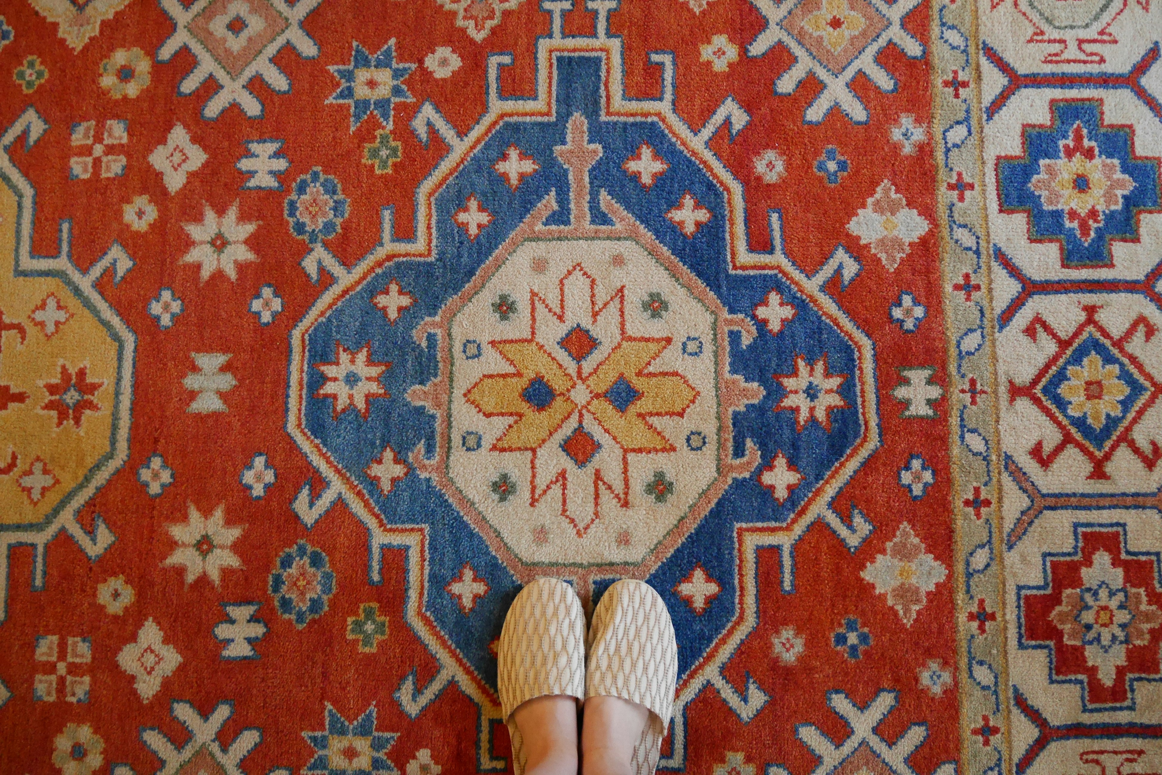 Piedi in scarpe bianche su un tappeto rosso decorato