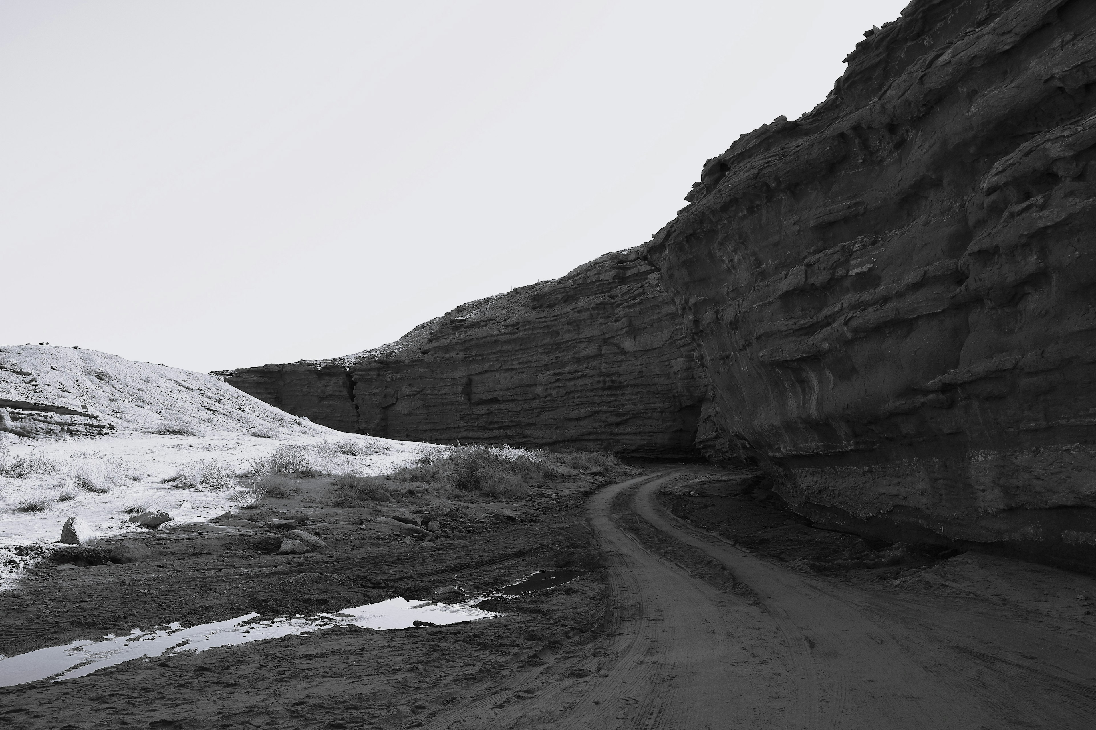 Curved path alongside a high cliff in a black and white landscape