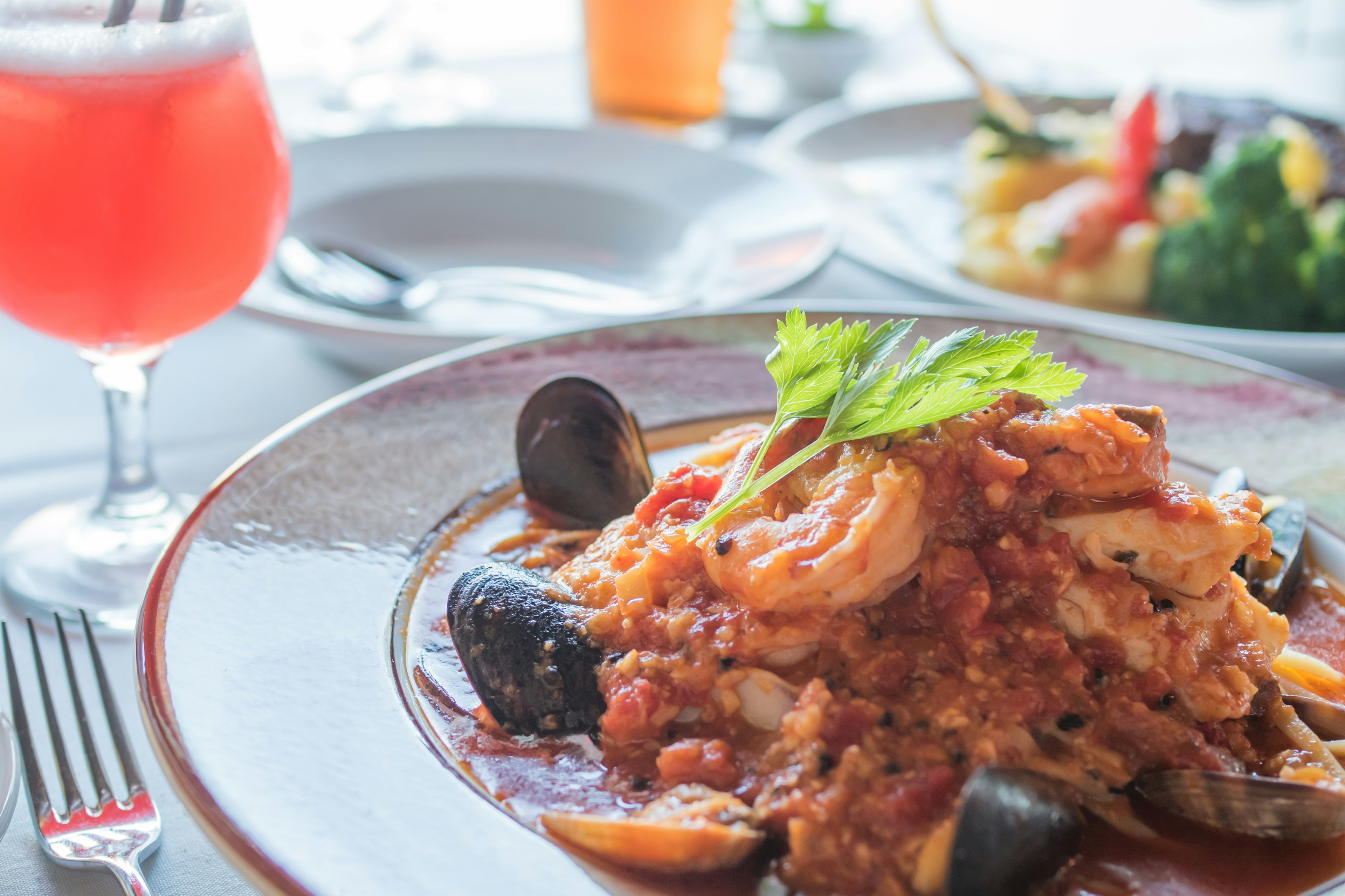 Ein Teller Meeresfrüchte-Pasta mit Garnelen und Muscheln neben einem lebhaften Cocktail