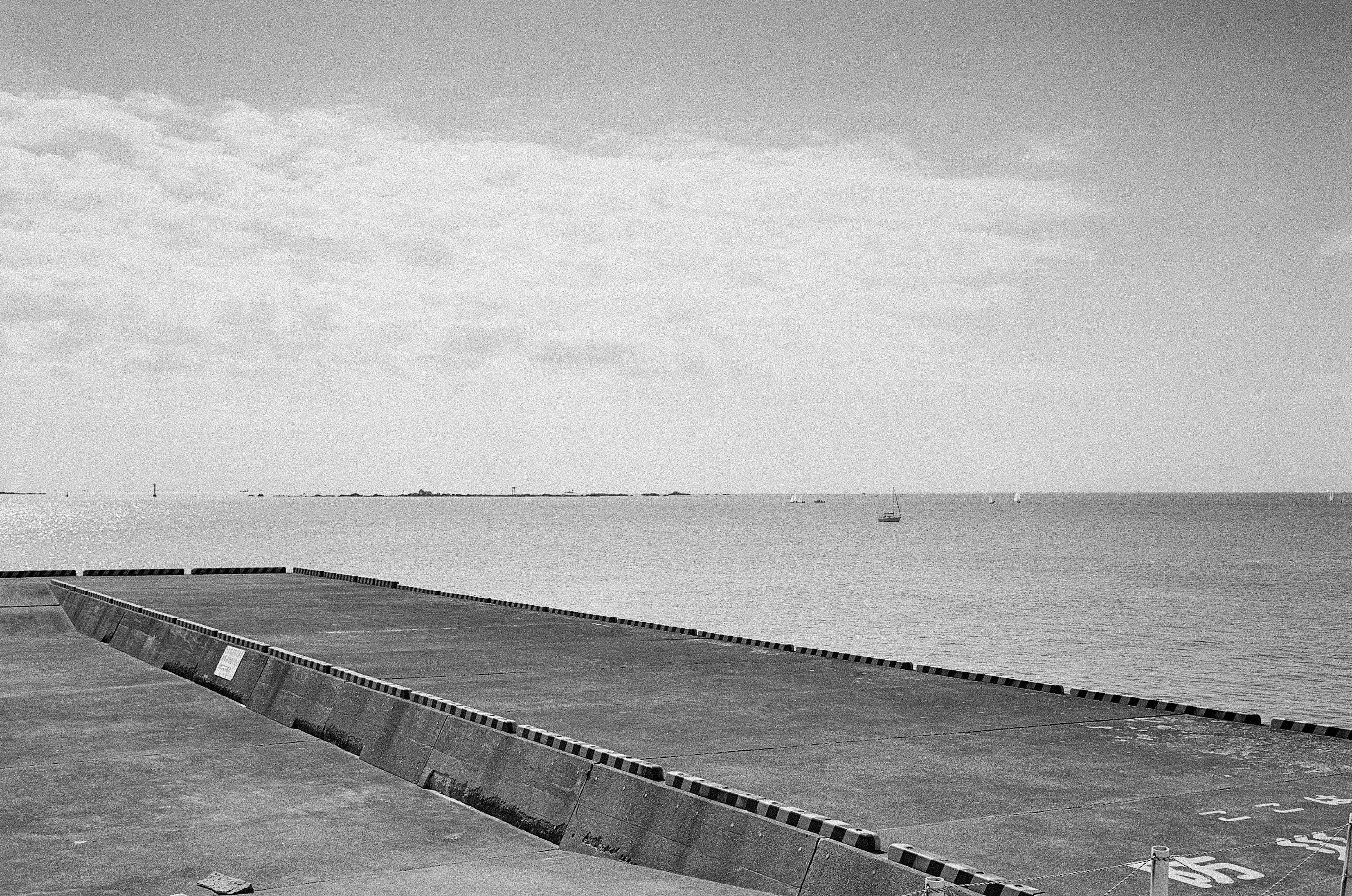 Concrete pier extending into the sea with a calm sky