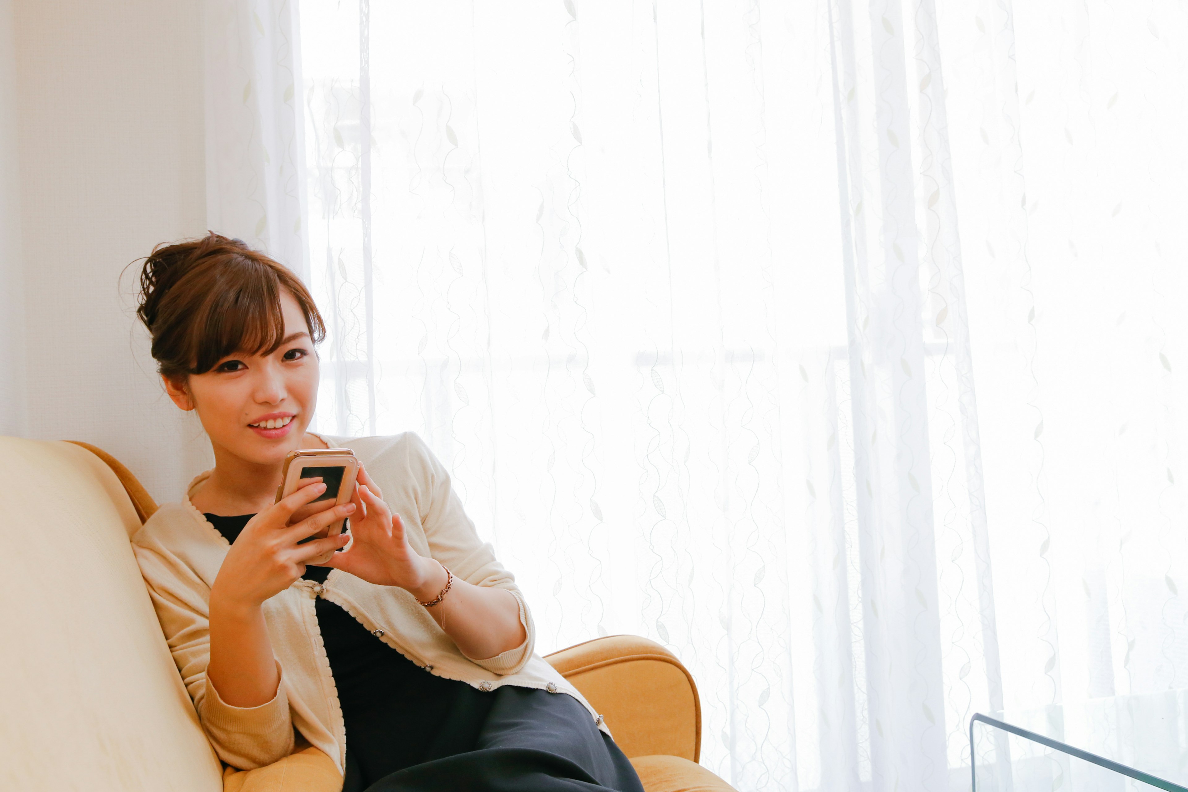 Retrato de una mujer sentada en un sofá sosteniendo un teléfono inteligente