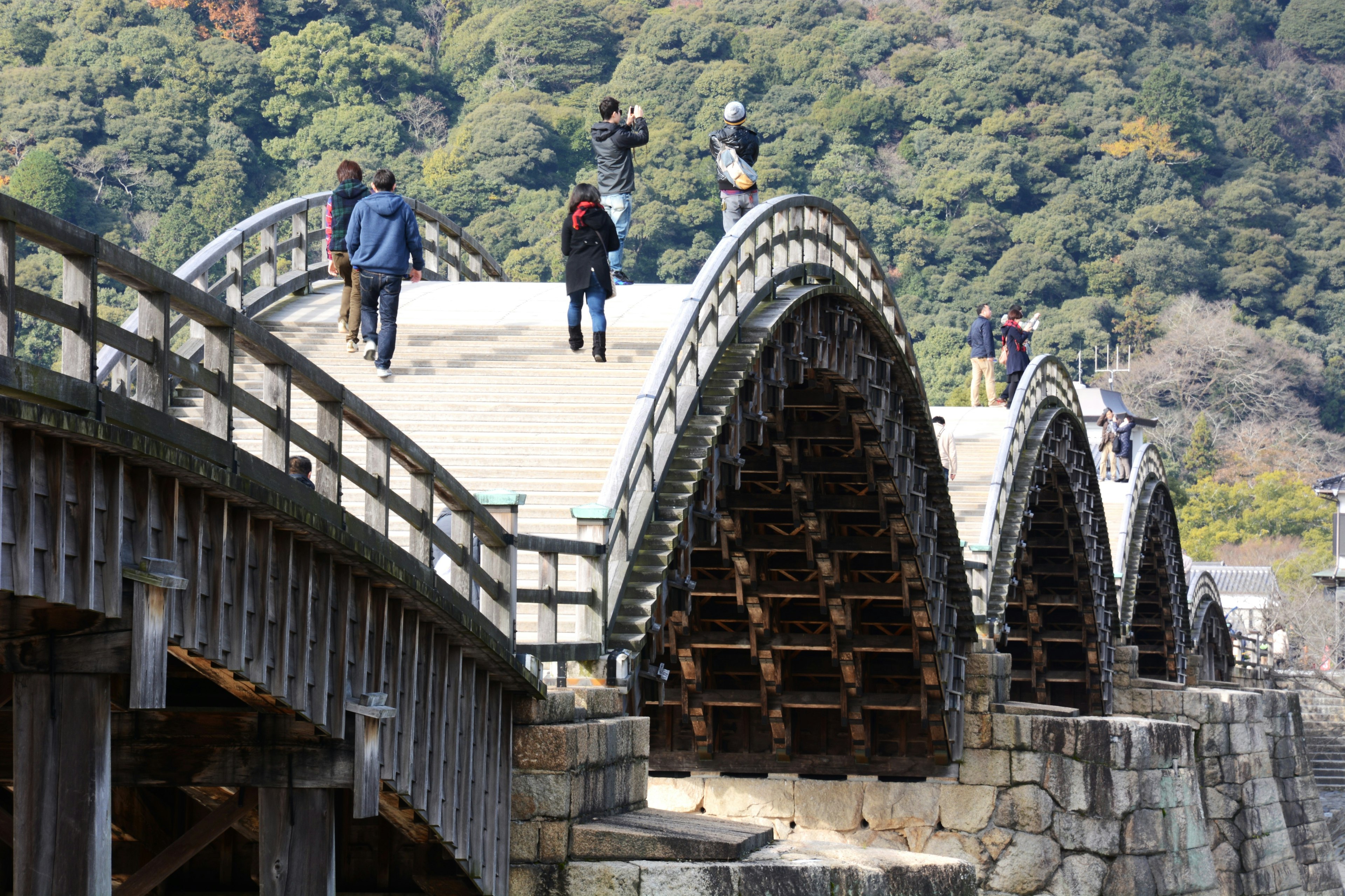 Aussicht auf eine hölzerne Bogenbrücke mit Menschen, die gehen