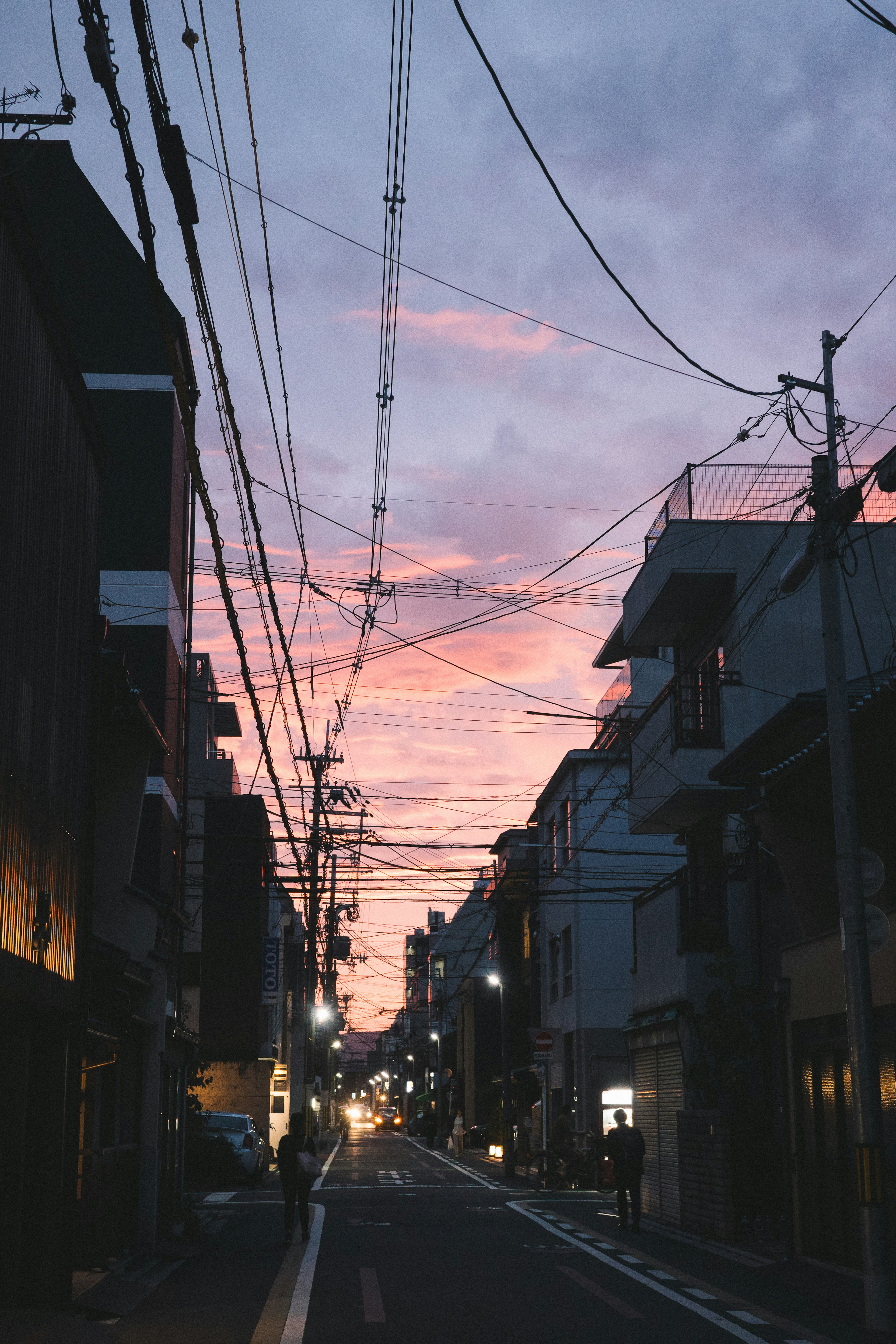 Vista de una calle tranquila al anochecer con edificios y líneas eléctricas