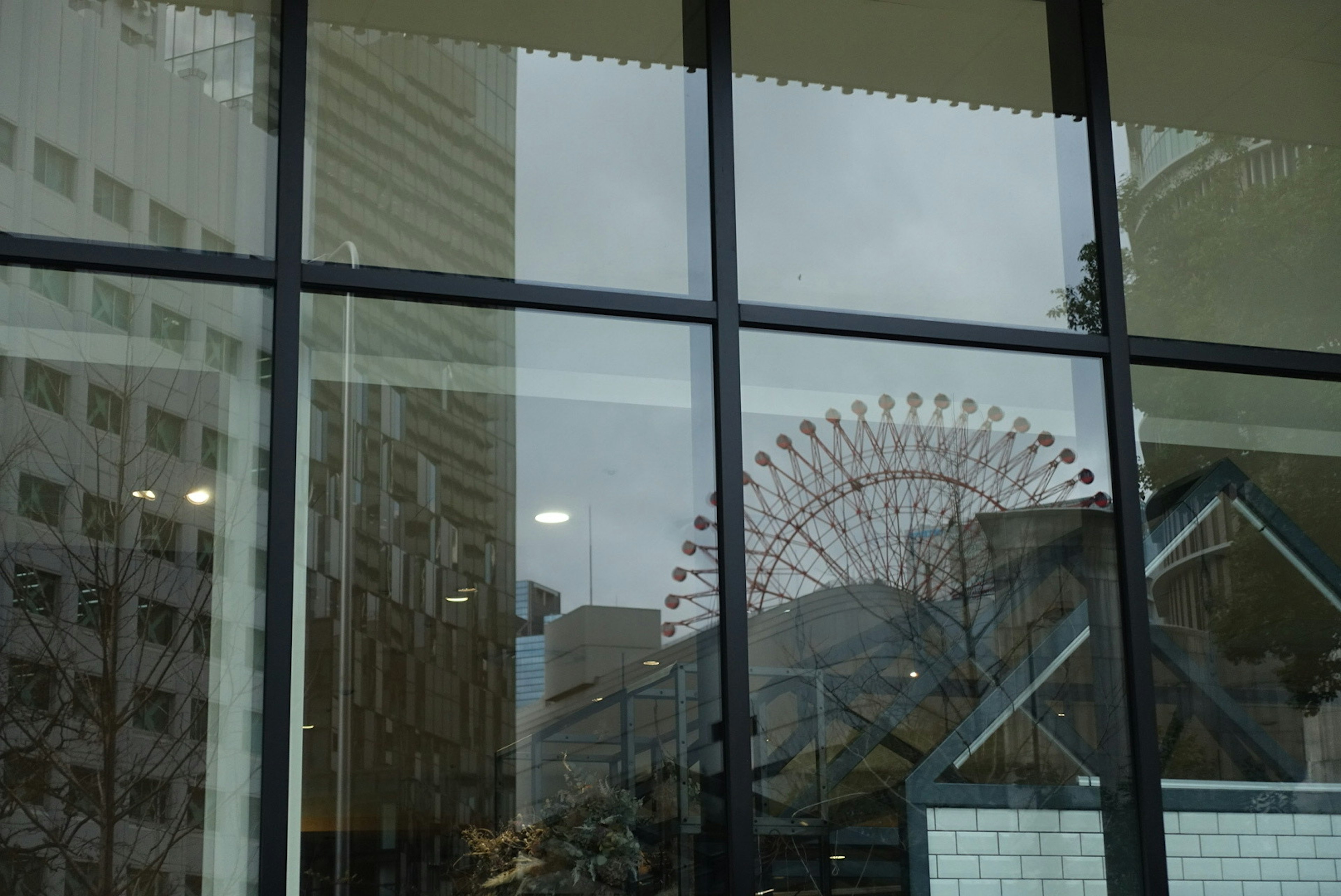 Réflexion d'une grande roue et paysage urbain dans une fenêtre