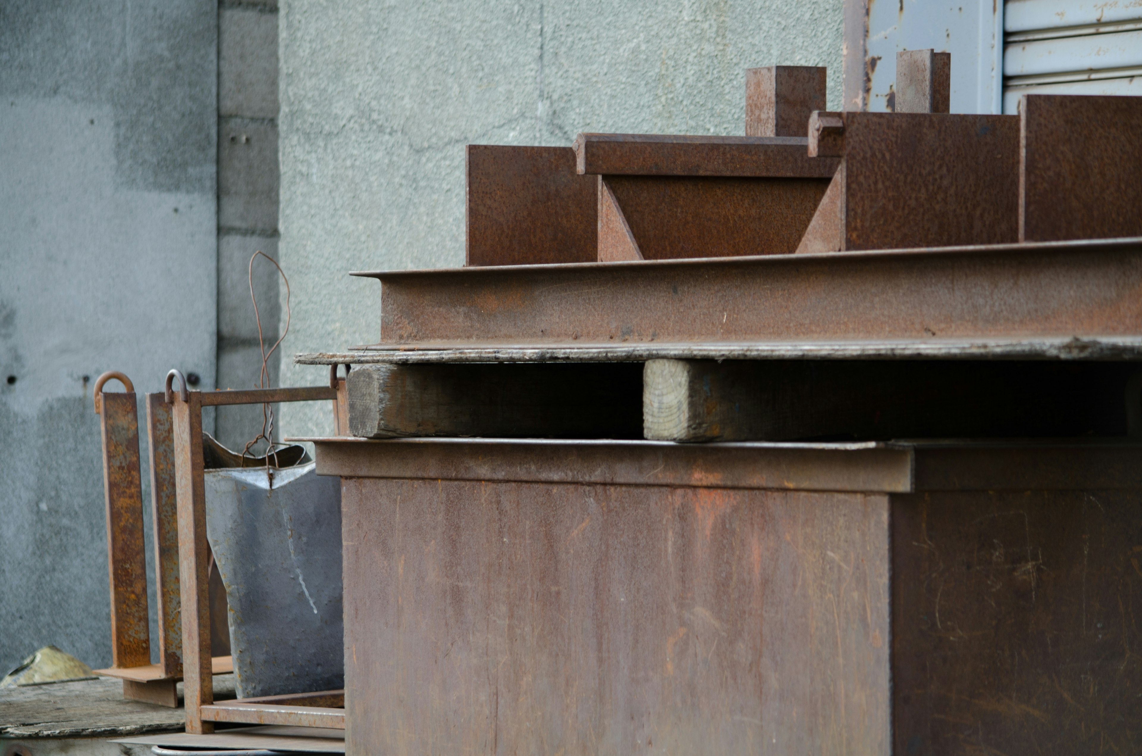 Rusty metal structures stacked on wooden pallets in an industrial setting