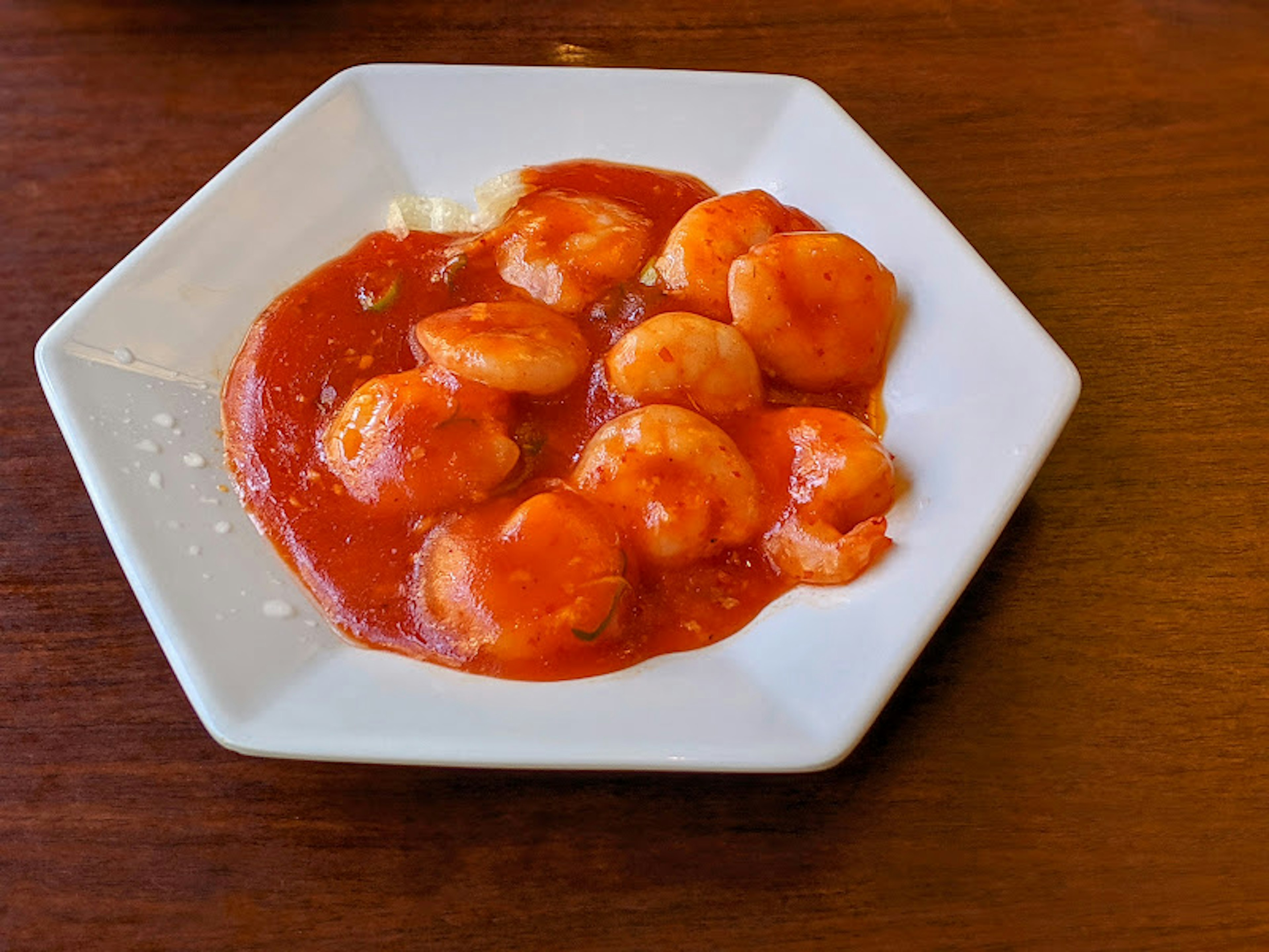 Shrimp in tomato sauce served on a hexagonal plate