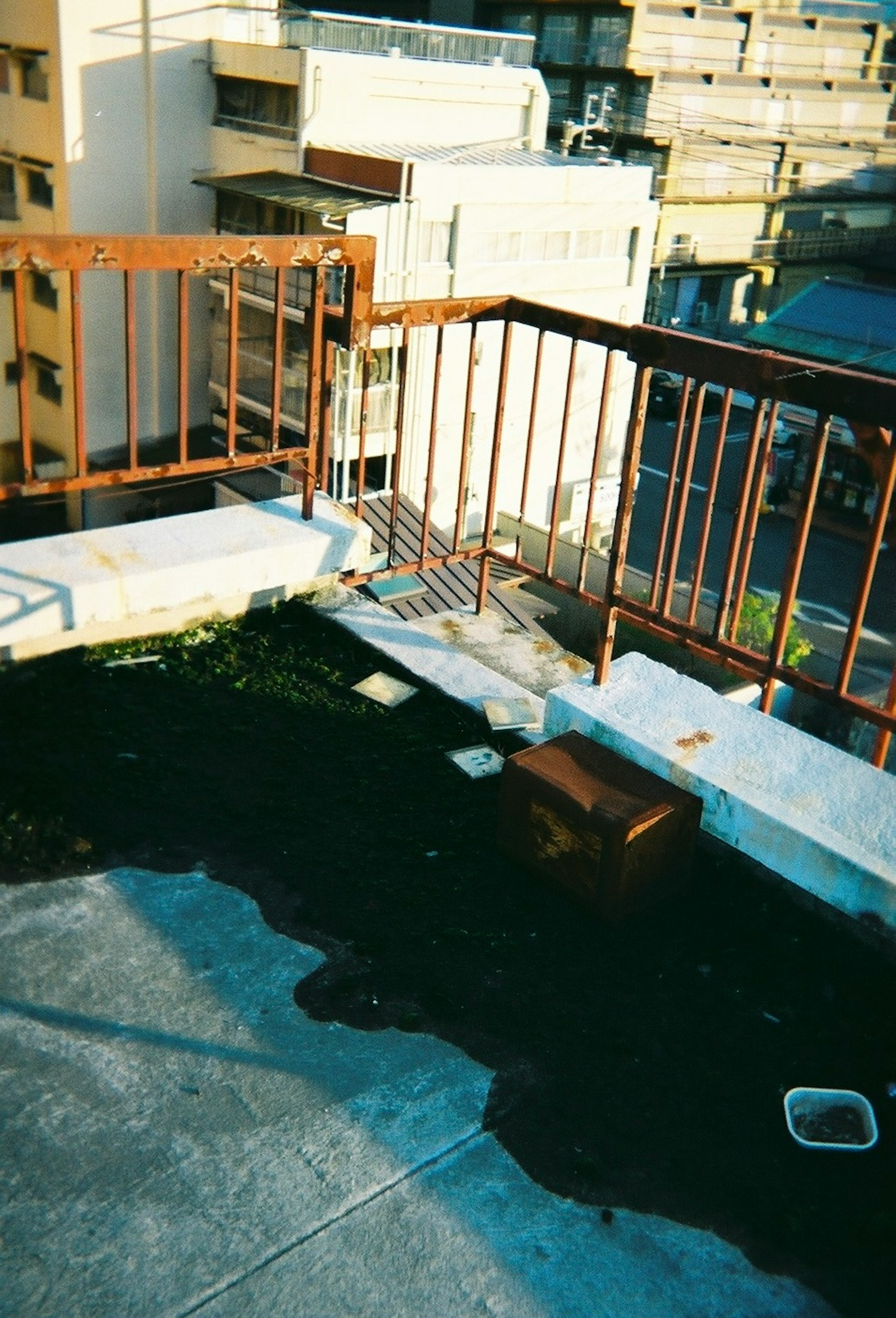 View of an old apartment balcony featuring rusty railing and concrete floor