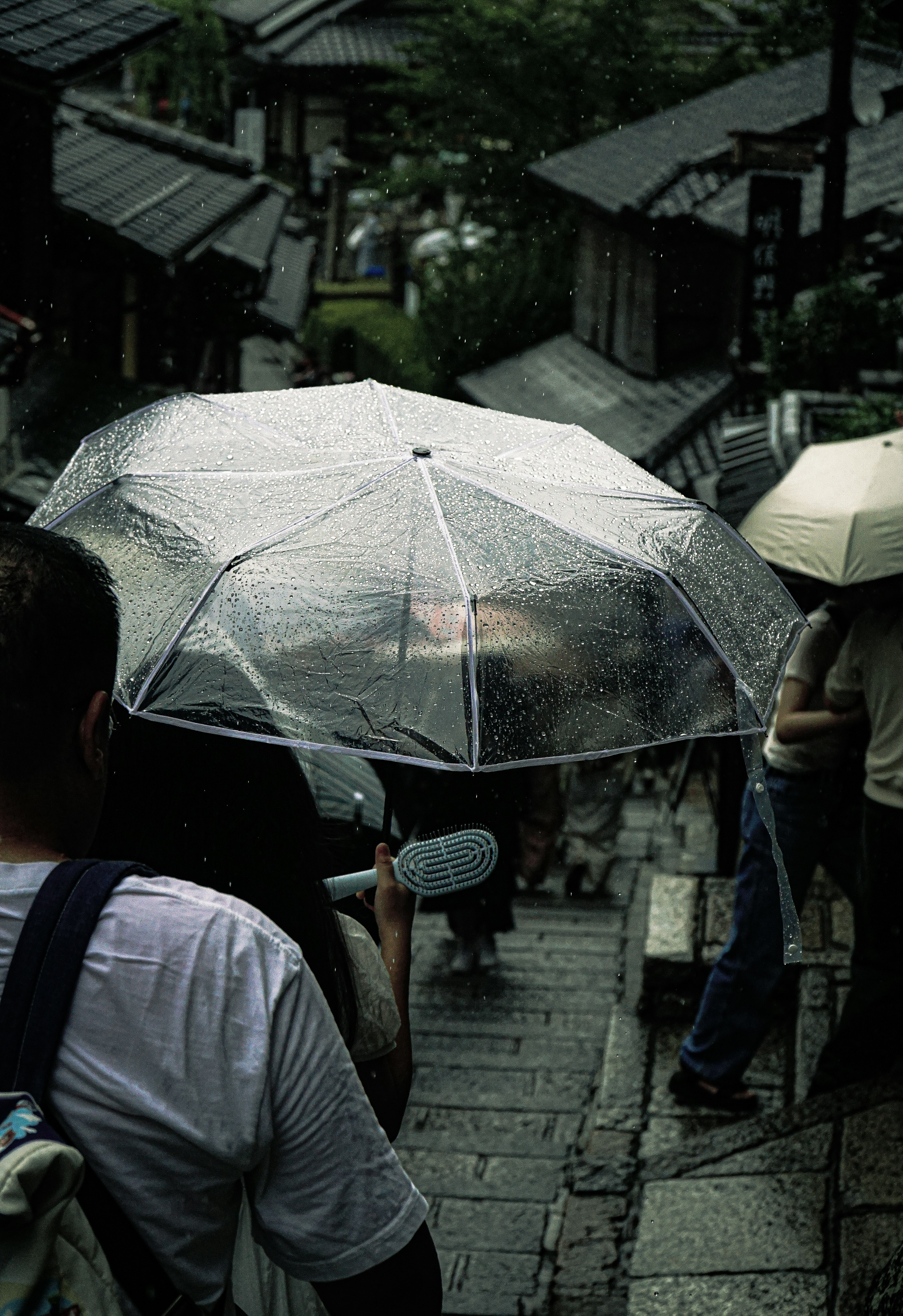 人們在雨中撐著傘下樓梯