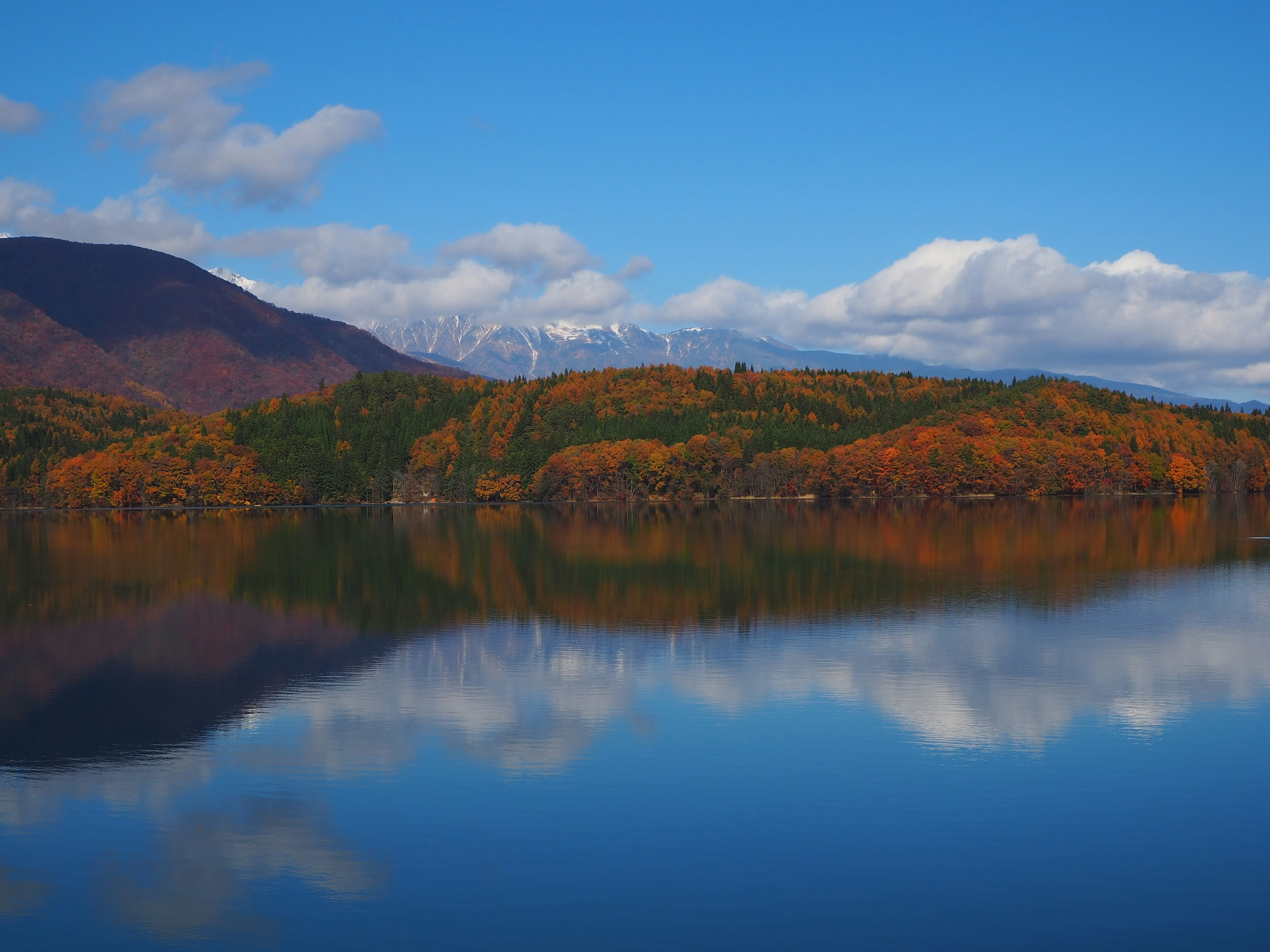 Beau paysage d'automne avec des arbres colorés reflétés sur la surface calme du lac et ciel bleu