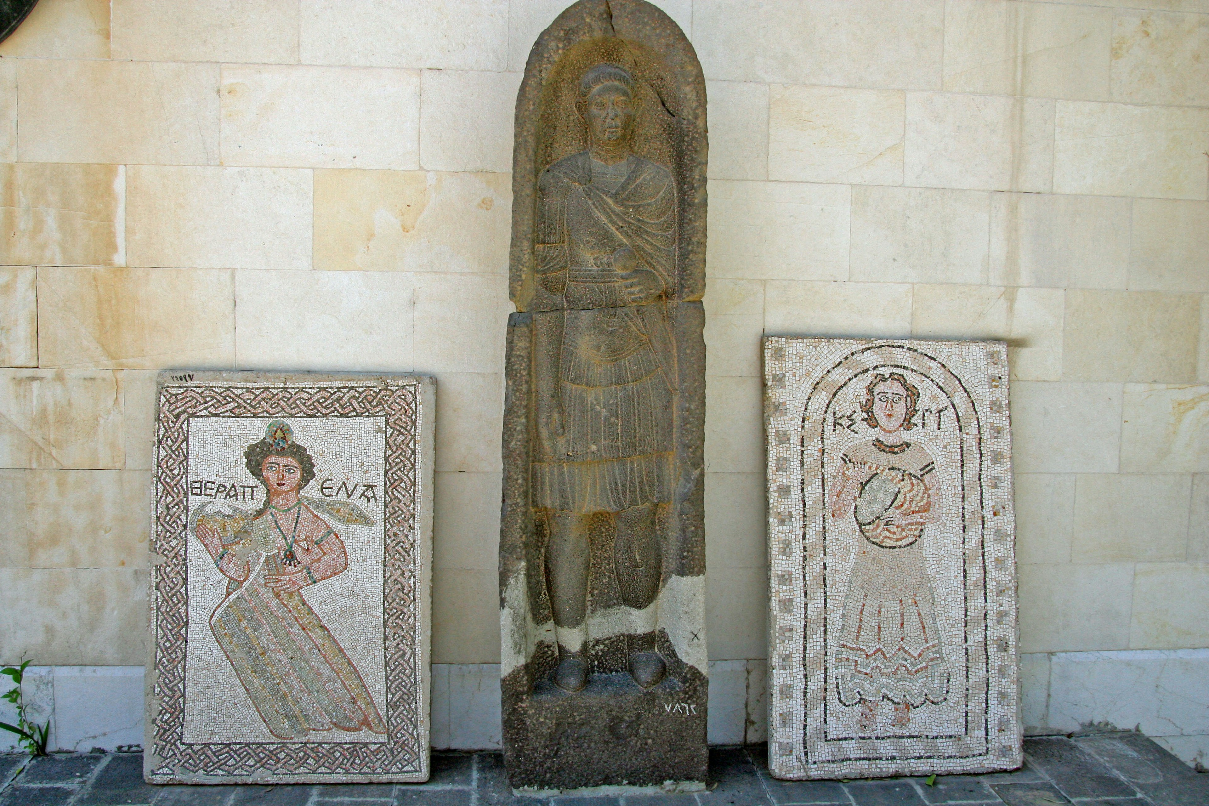 Historical display featuring a stone sculpture and mosaic artworks