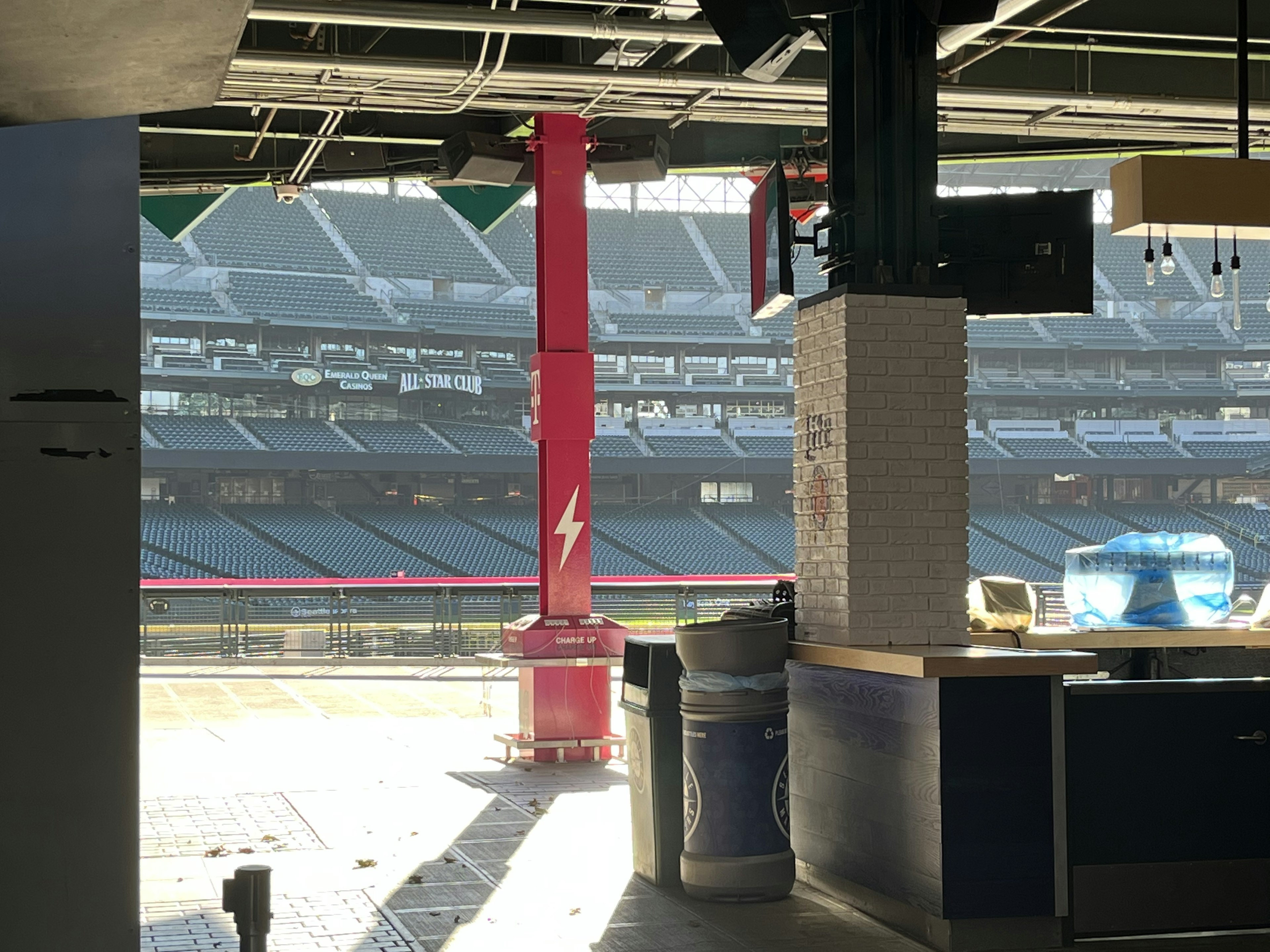 Vista interna di uno stadio con un pilastro rosso davanti a un chiosco e posti vuoti