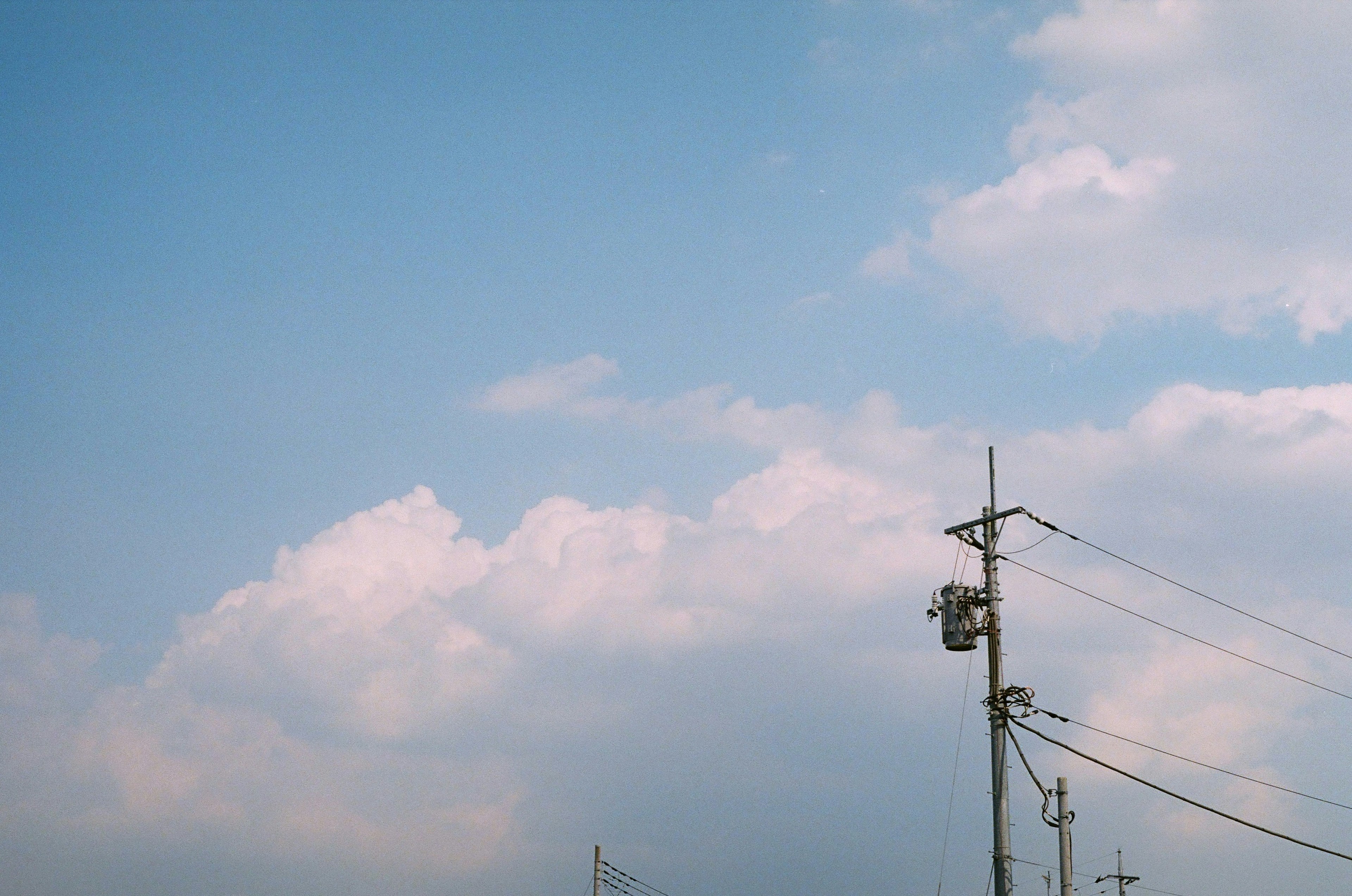 Vue panoramique d'un ciel bleu avec des nuages blancs et des poteaux électriques