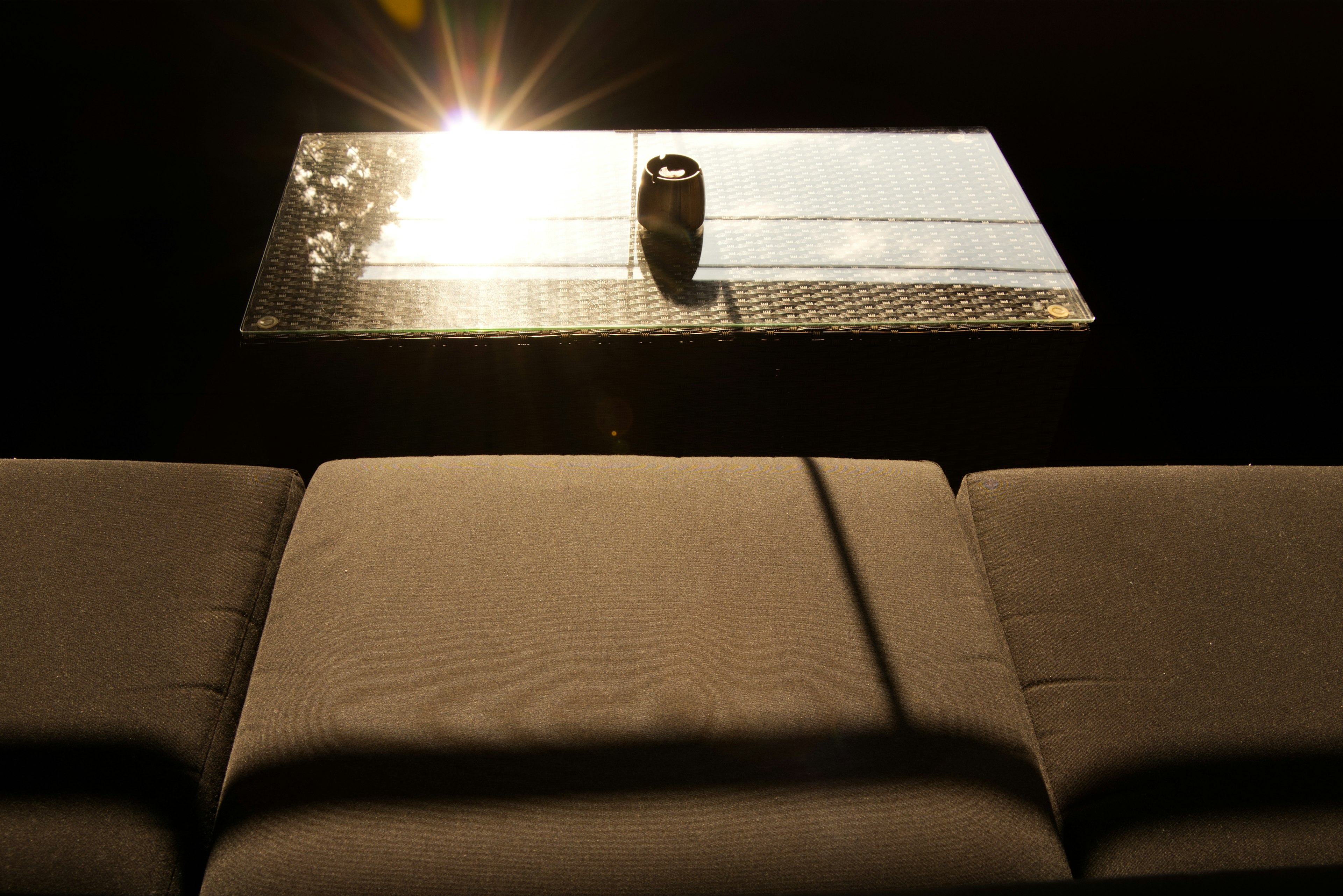 A view of a sofa with a table reflecting sunlight and a small object on top