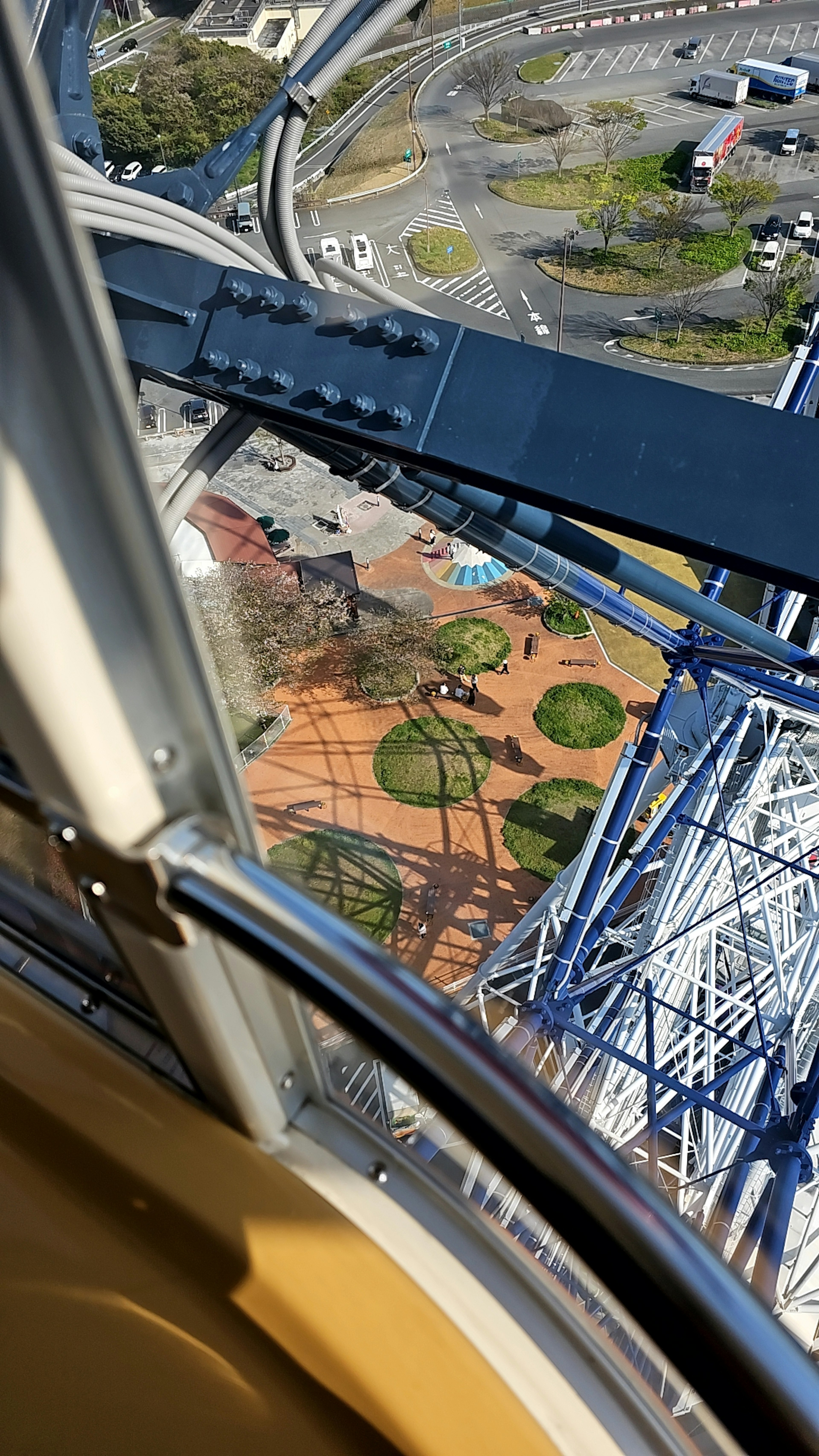 View from a Ferris wheel showing circular green areas in a park below