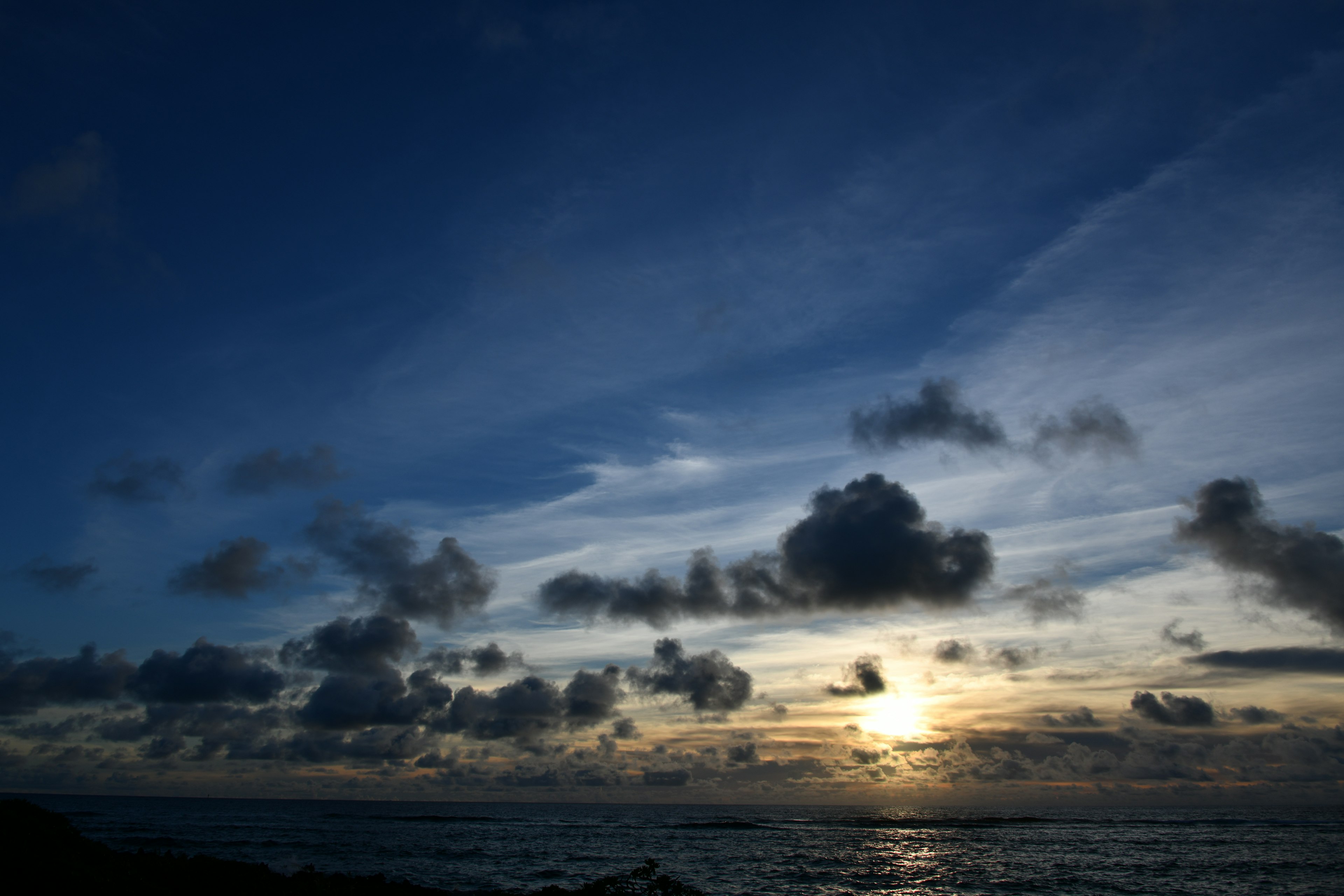 A scenic view of a sunset over the ocean with dramatic clouds