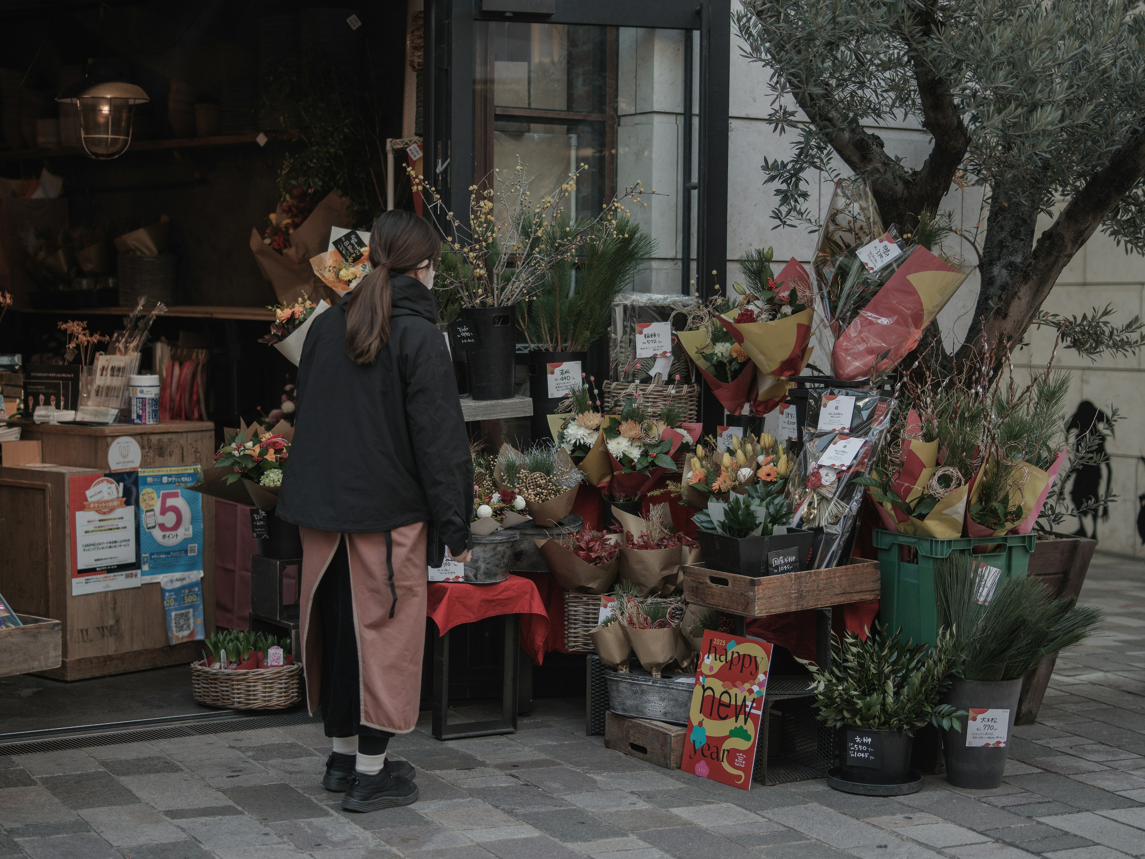 花屋の前に立つ女性 色とりどりの花が並ぶ店外