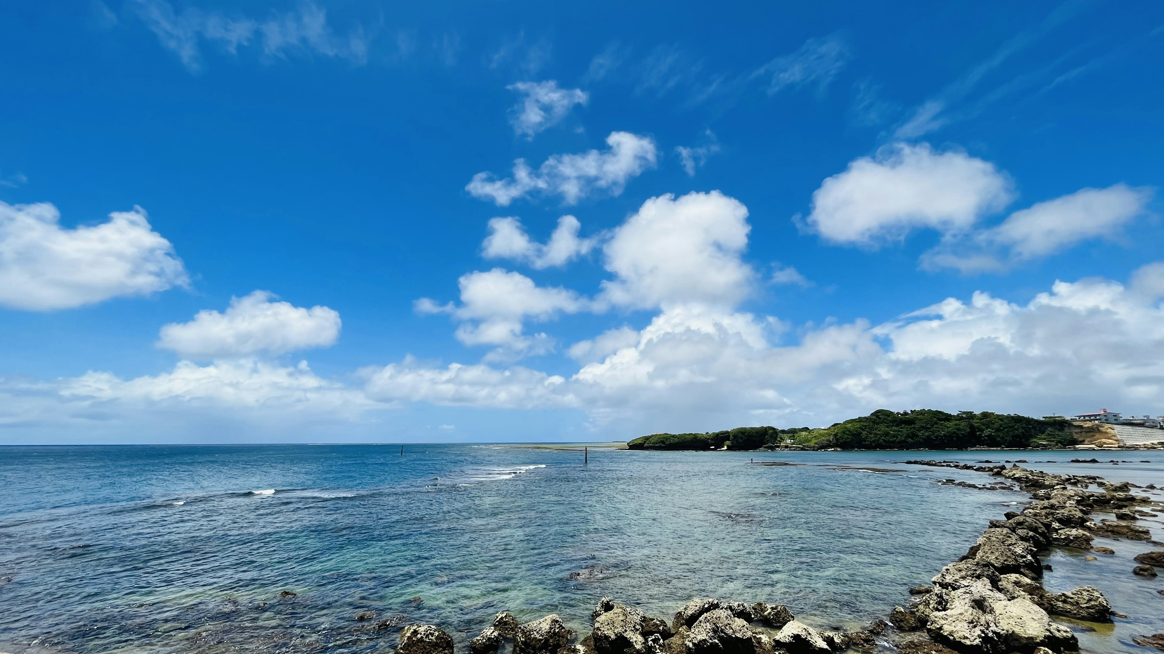 青い海と白い雲が広がる風景 岩が点在する海岸線の景色