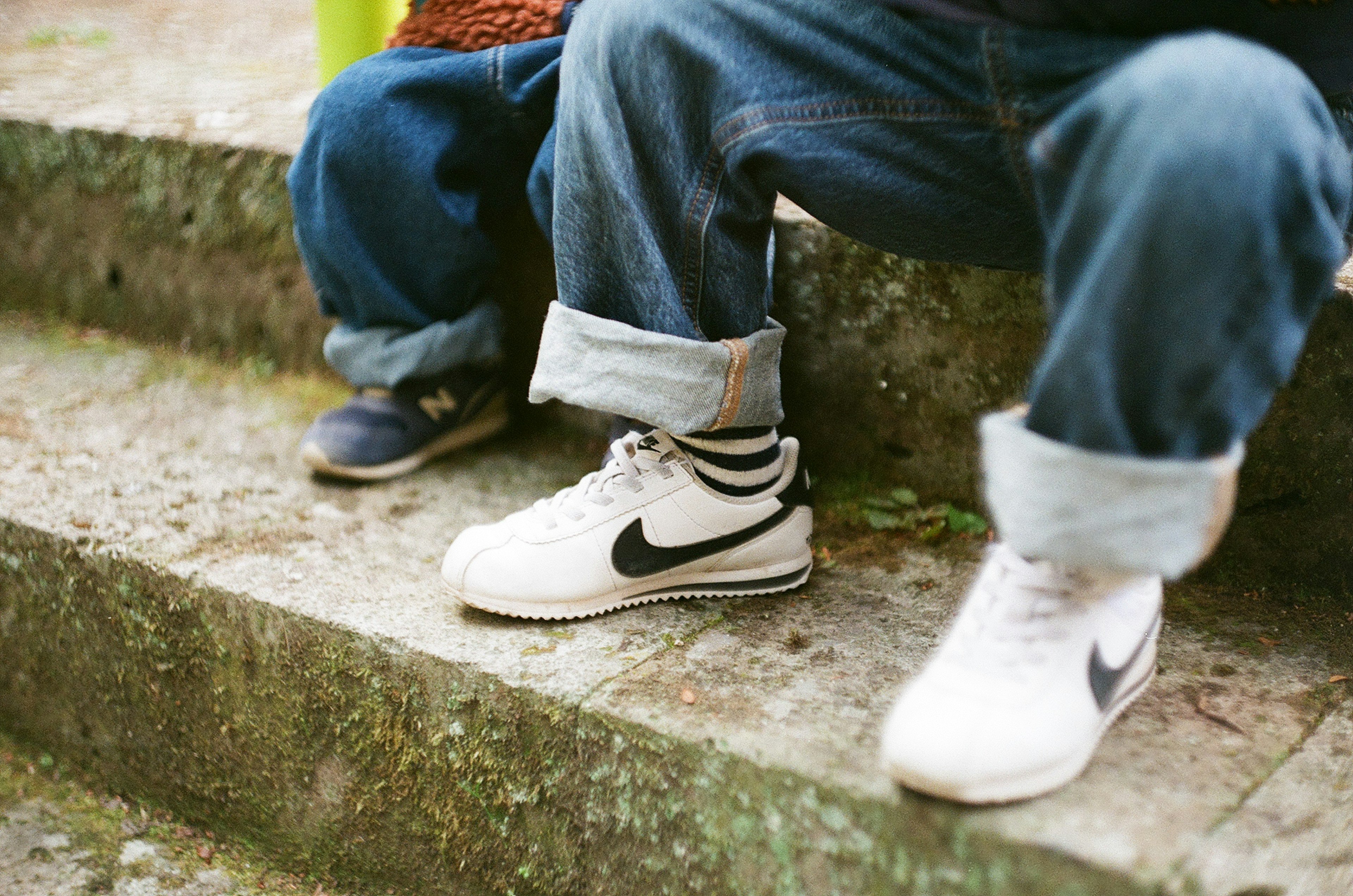 Füße von Kindern auf einer Parktreppe mit Jeans und Turnschuhen