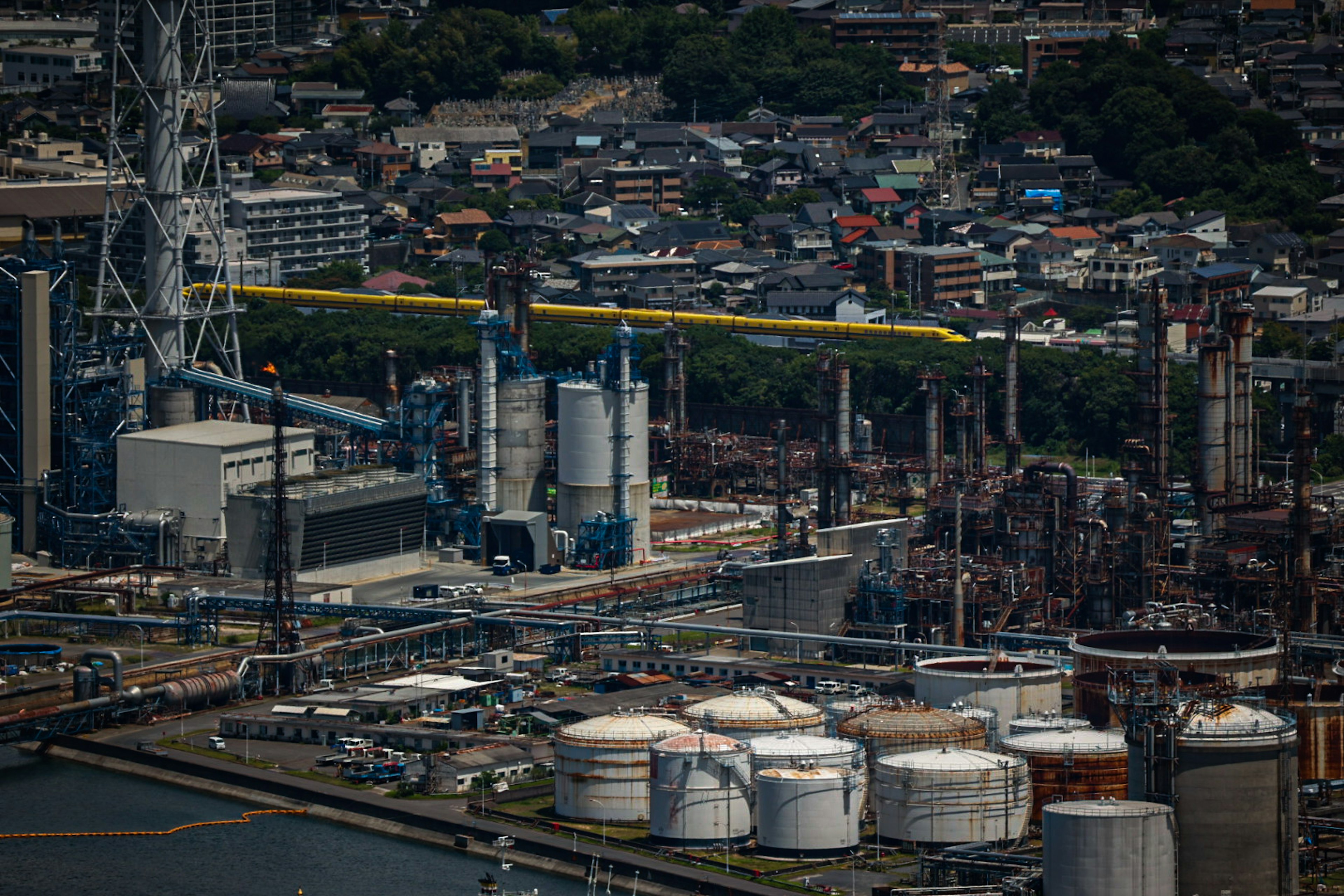 Luftaufnahme eines Industriegebiets mit Lagertanks Fabriken und urbanem Hintergrund