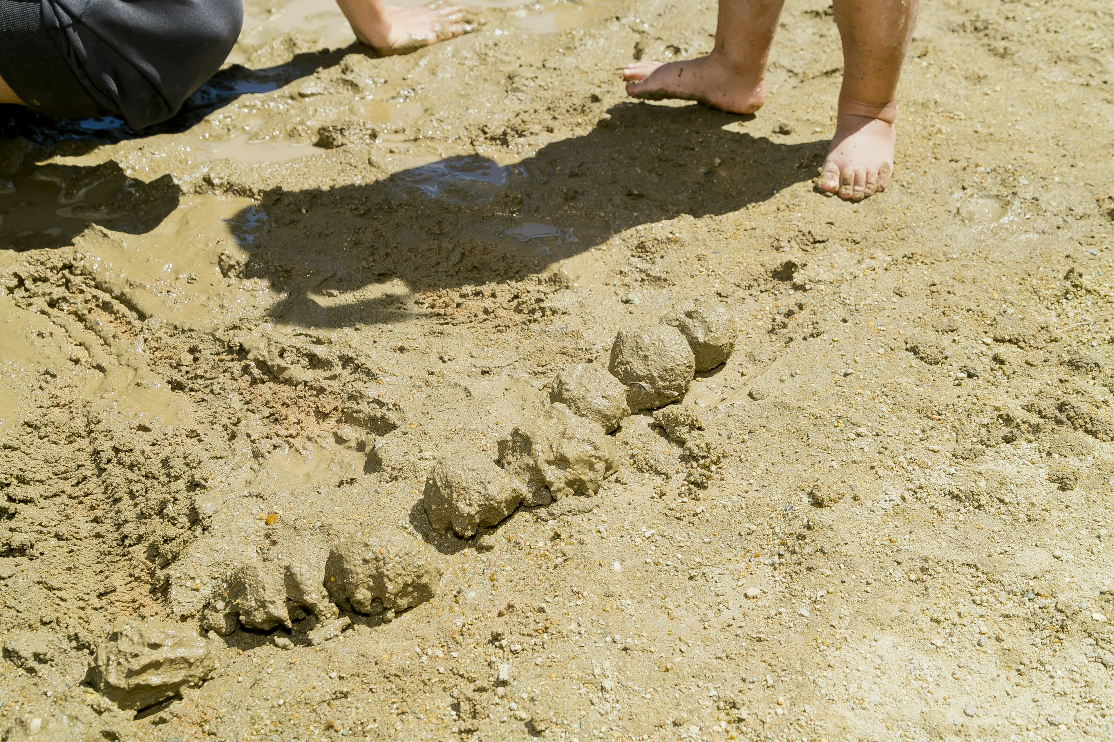 Una serie di cumuli di sabbia su una spiaggia con piedi nudi nelle vicinanze