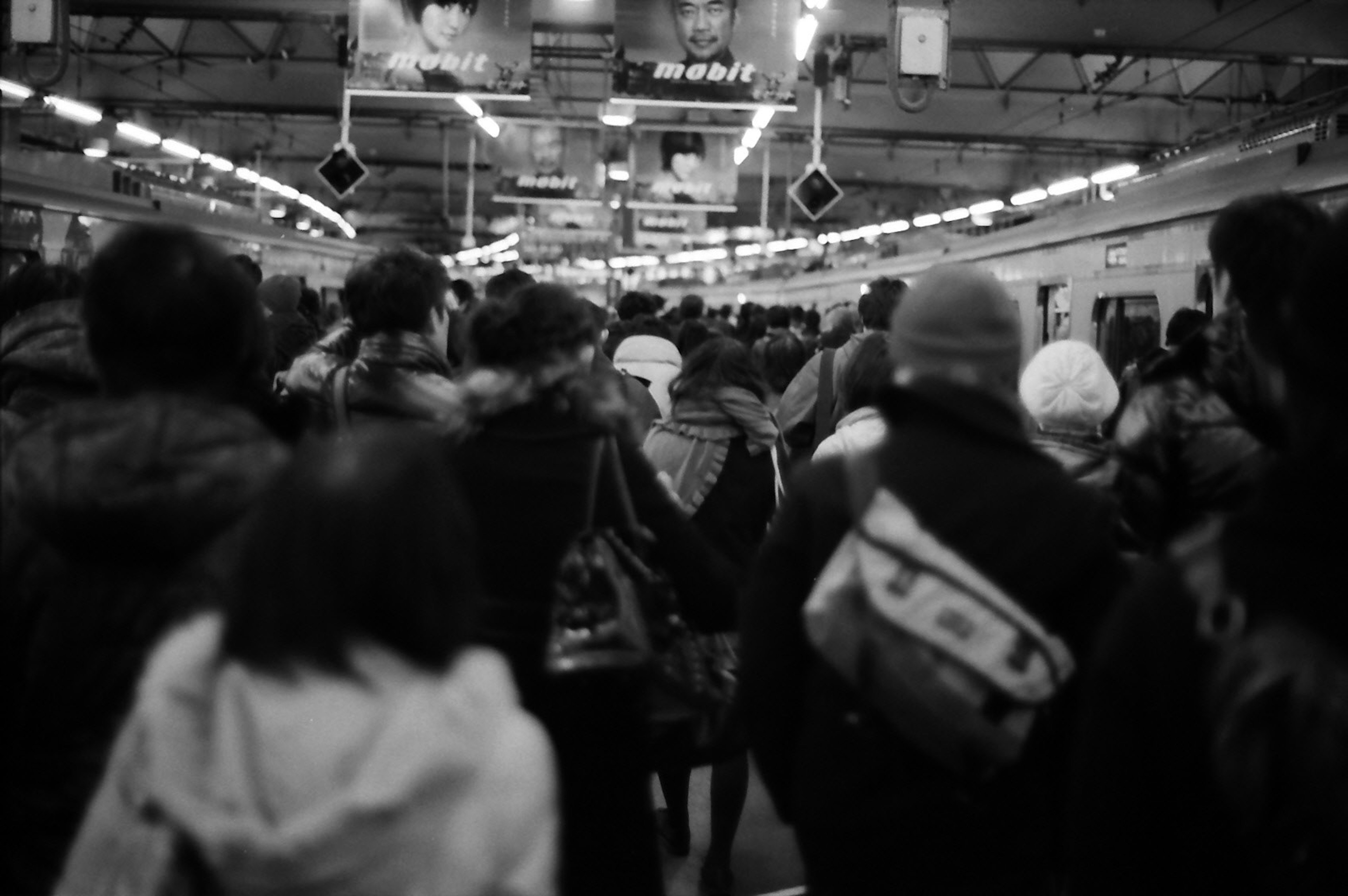 Black and white photo of a crowded train station platform with people moving