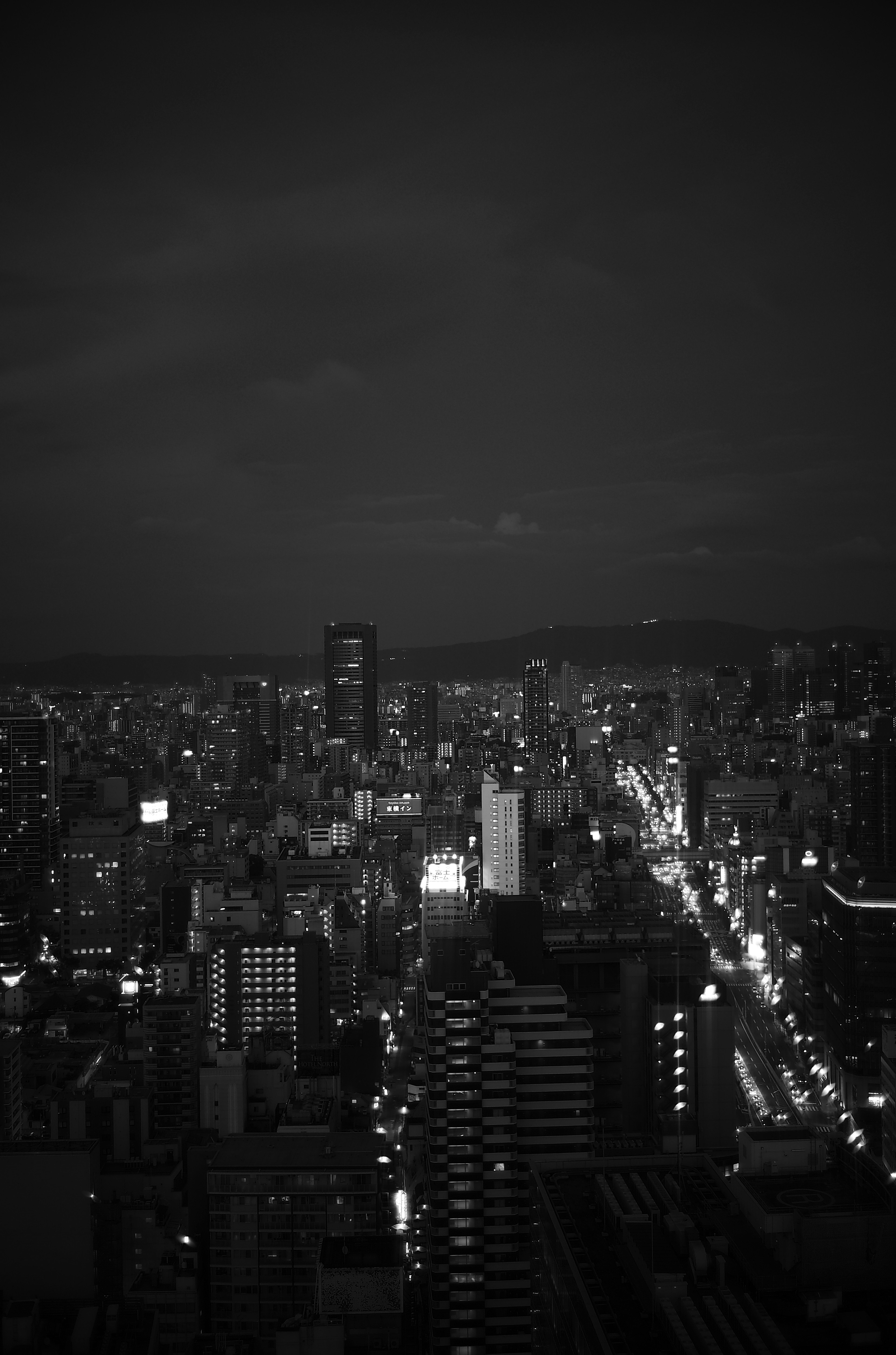 Black and white cityscape at night with illuminated buildings