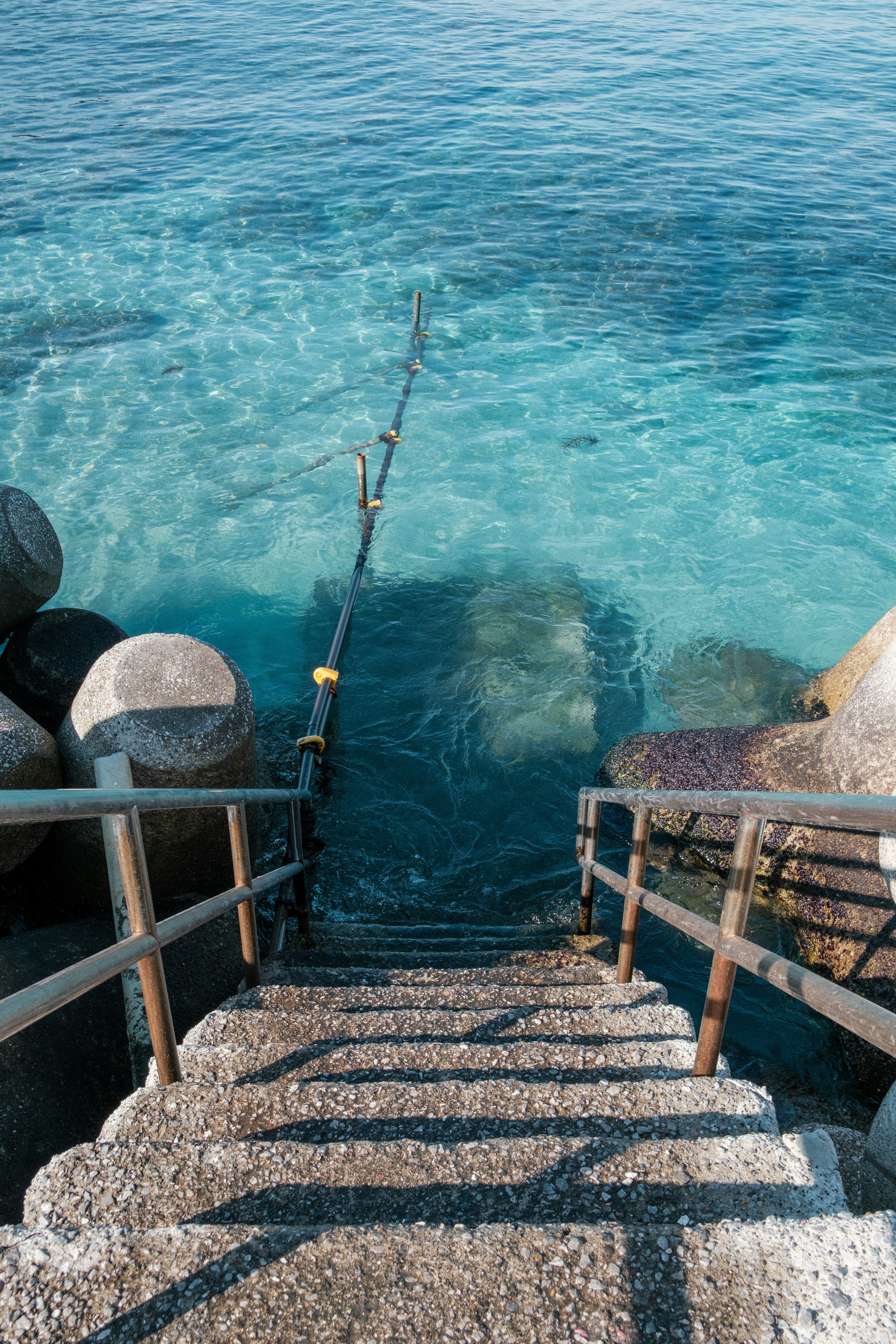 Stone steps leading into clear blue water with rocks