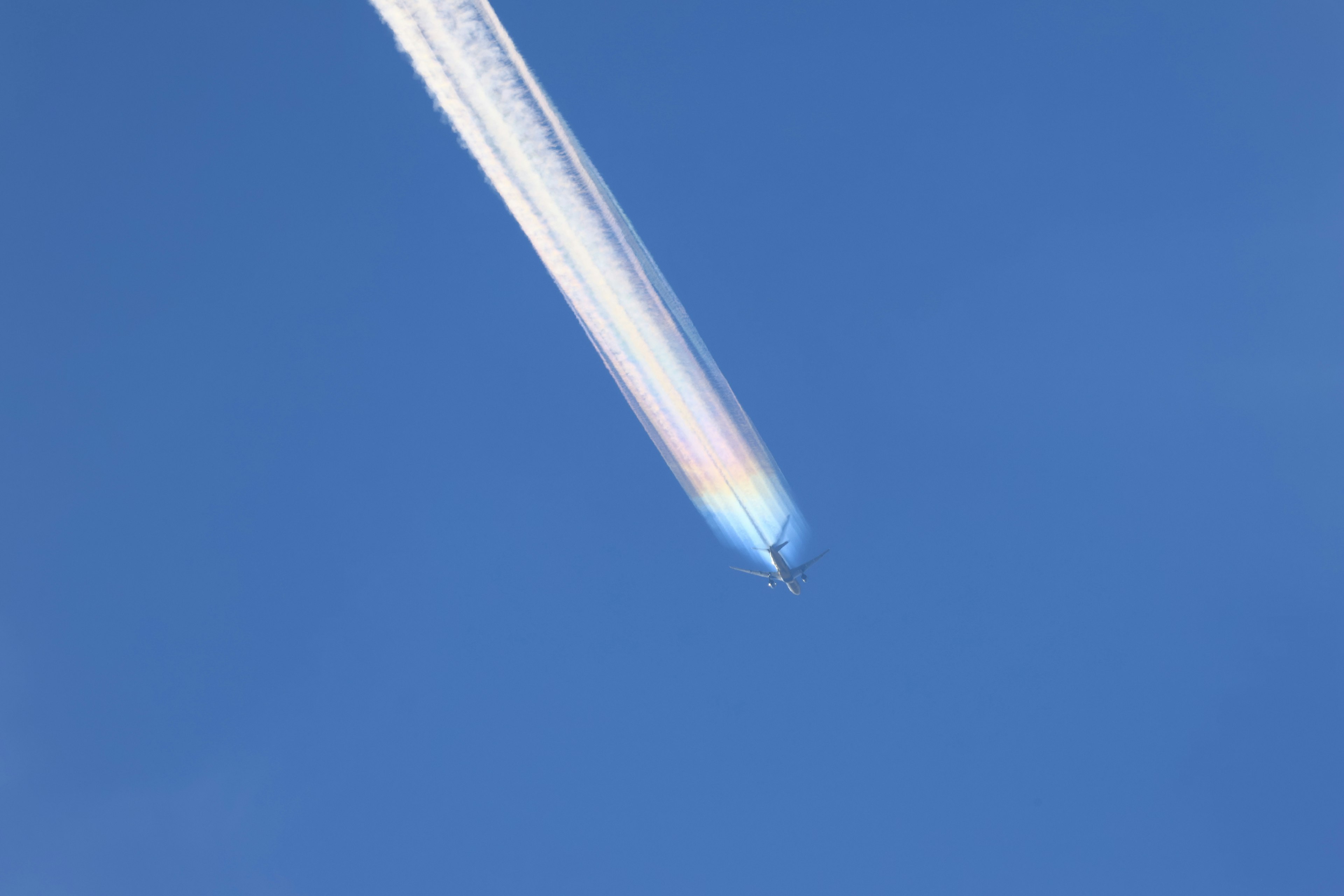 Colorful contrail from an aircraft against a blue sky