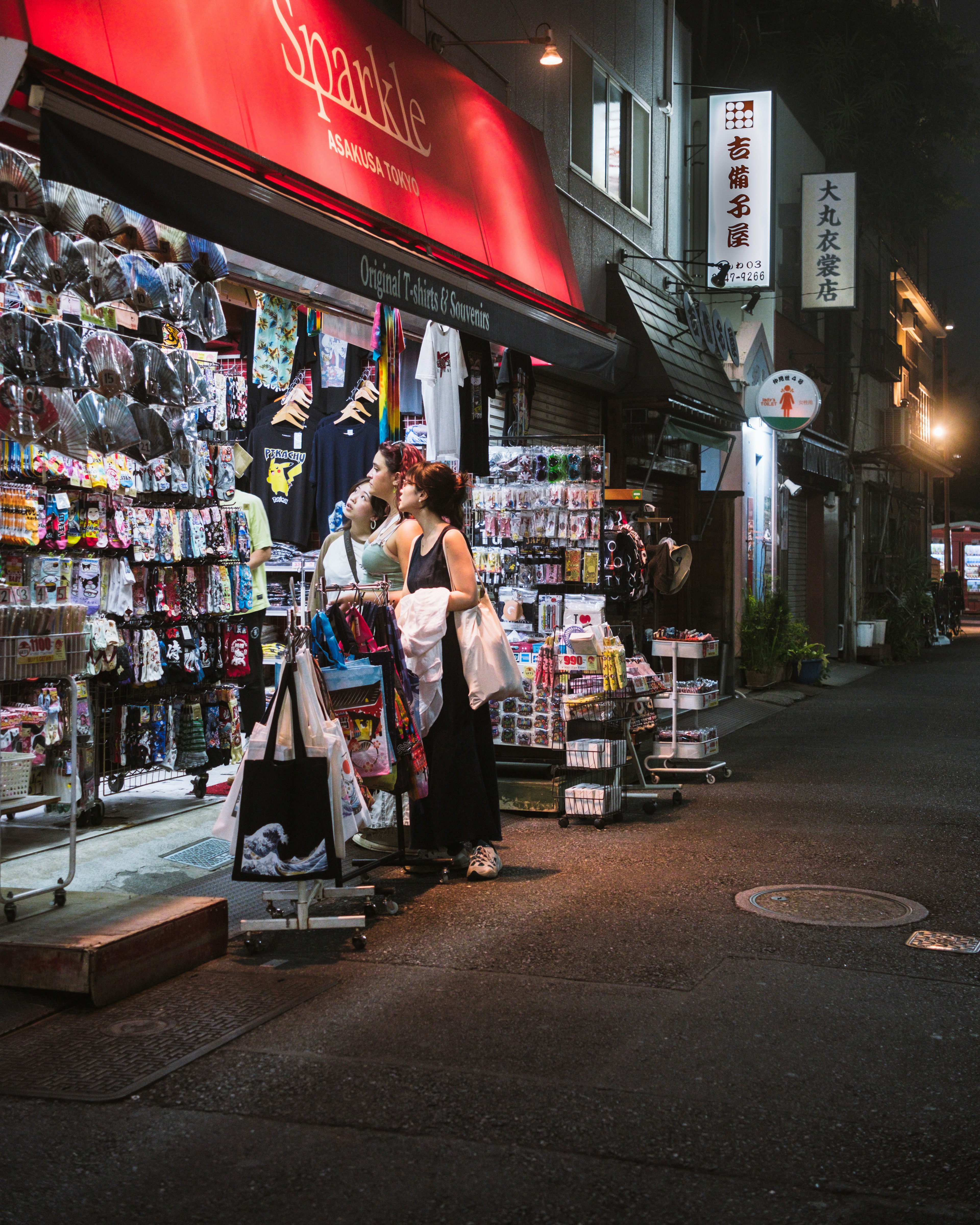 Une femme se tenant devant un magasin rempli de marchandises la nuit