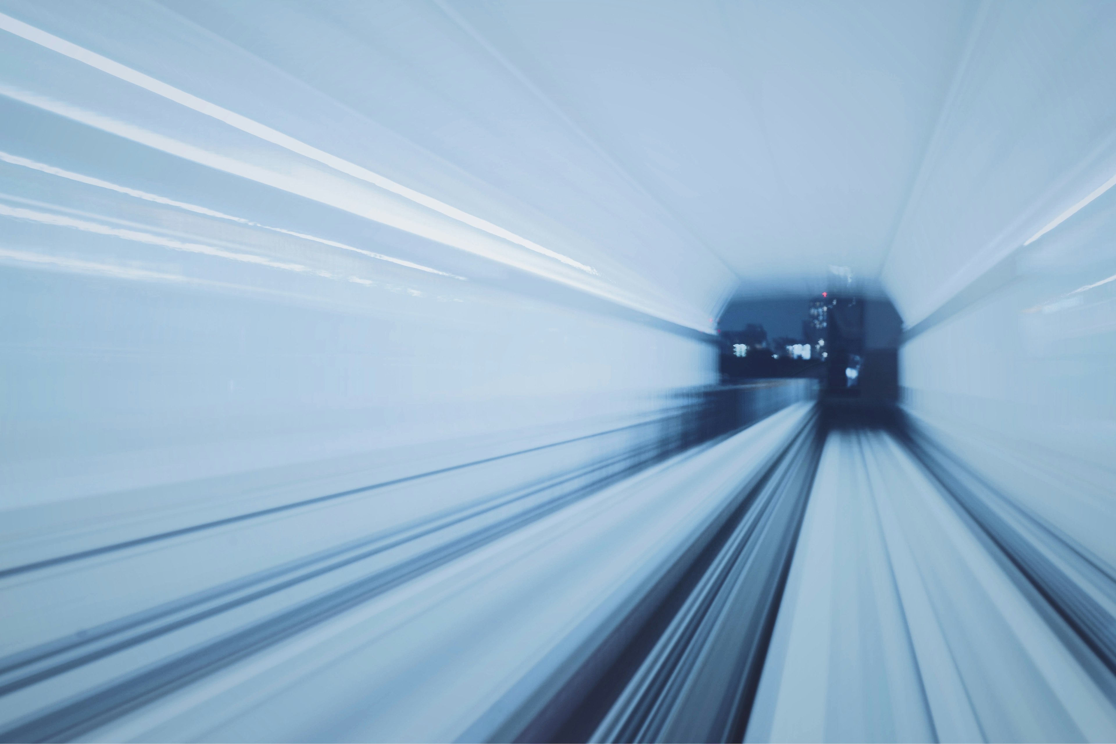 Verschommene Ansicht eines Zuges, der durch einen Tunnel mit blauen und weißen Lichtstreifen rast