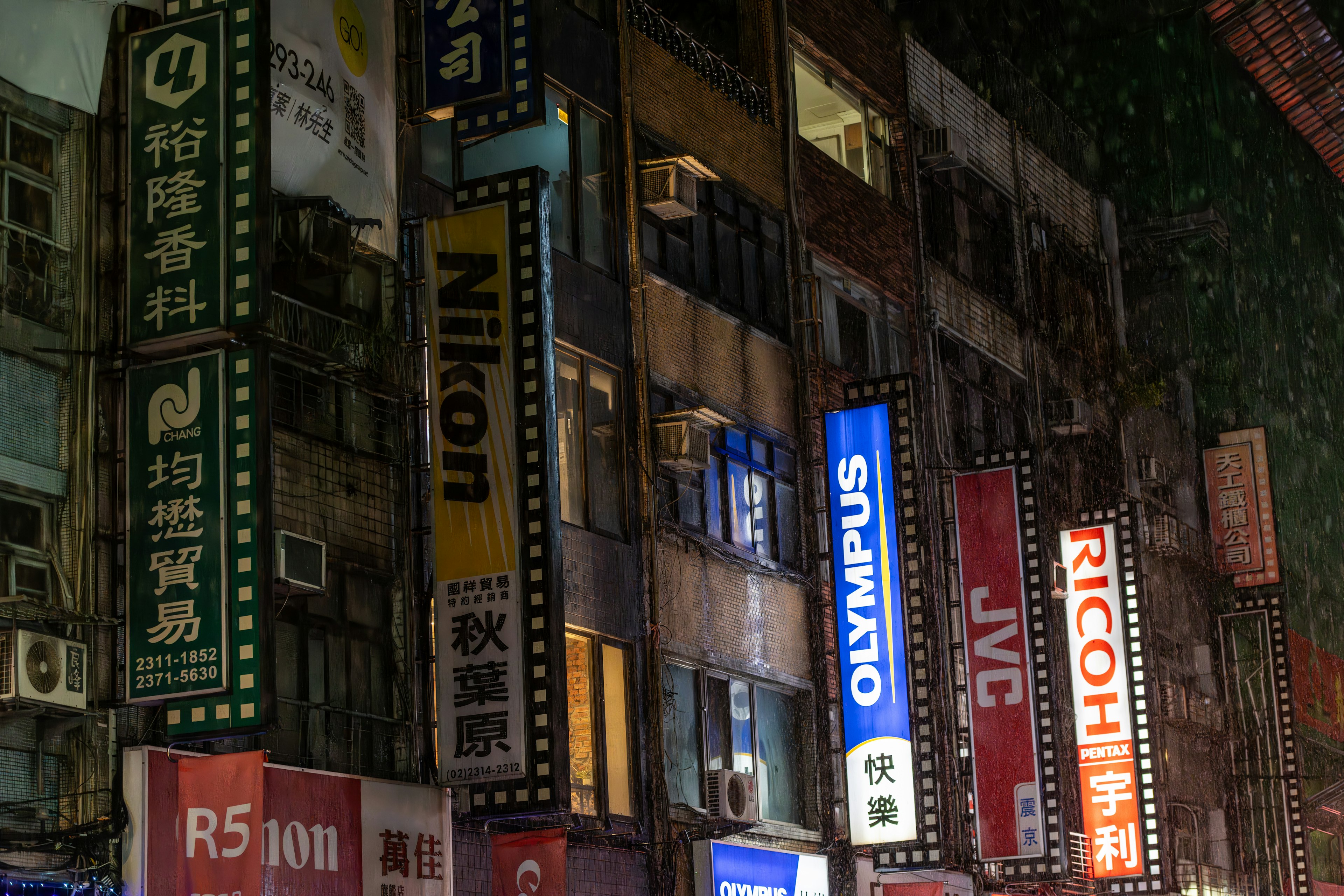 Insegne luminose di negozi di fotocamere in un contesto urbano notturno