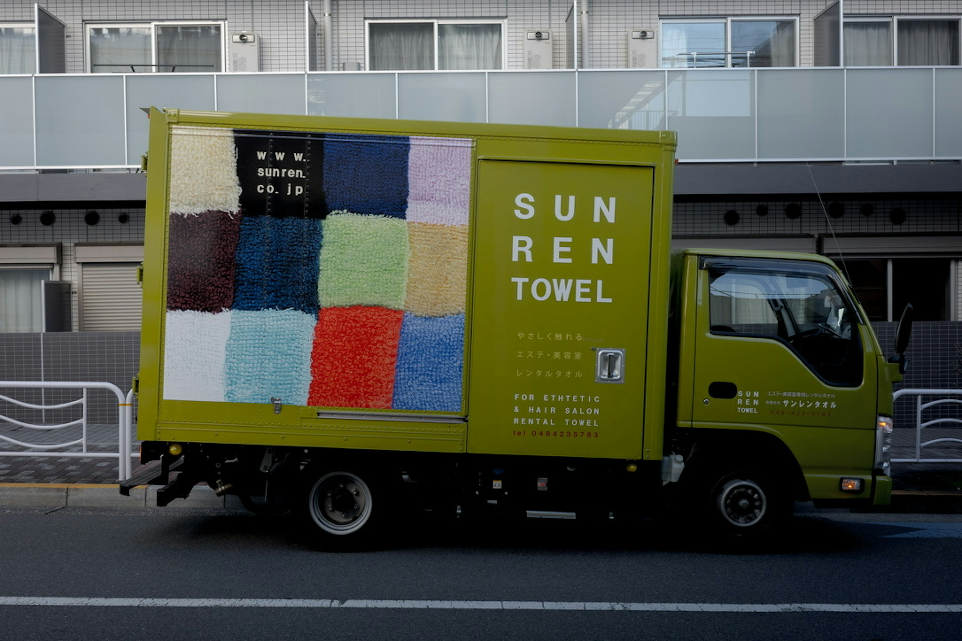 A yellow truck with colorful towels displayed on the side