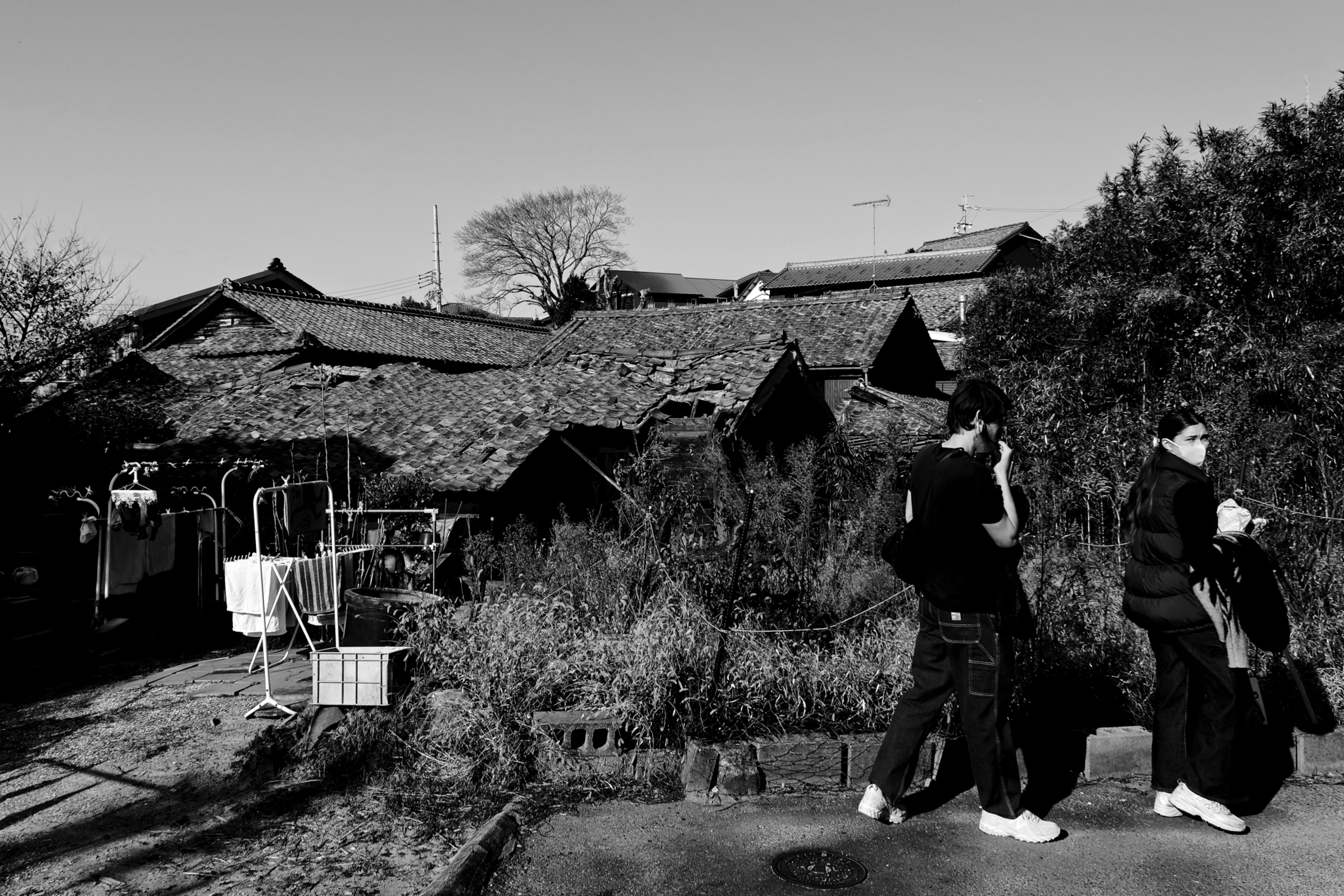 Escena en blanco y negro con casas tradicionales y dos personas caminando