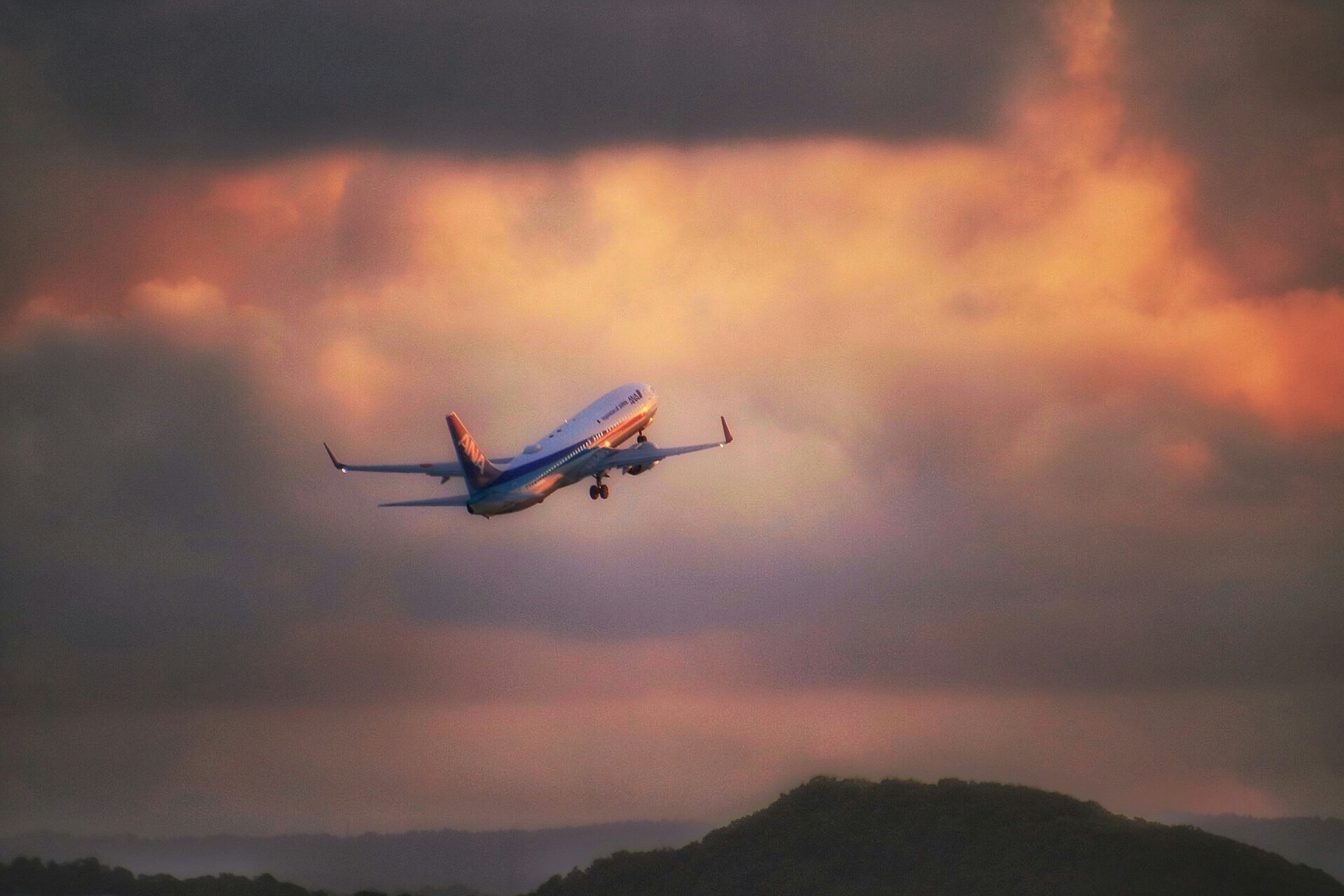 夕焼けの空を飛ぶ飛行機のシルエット