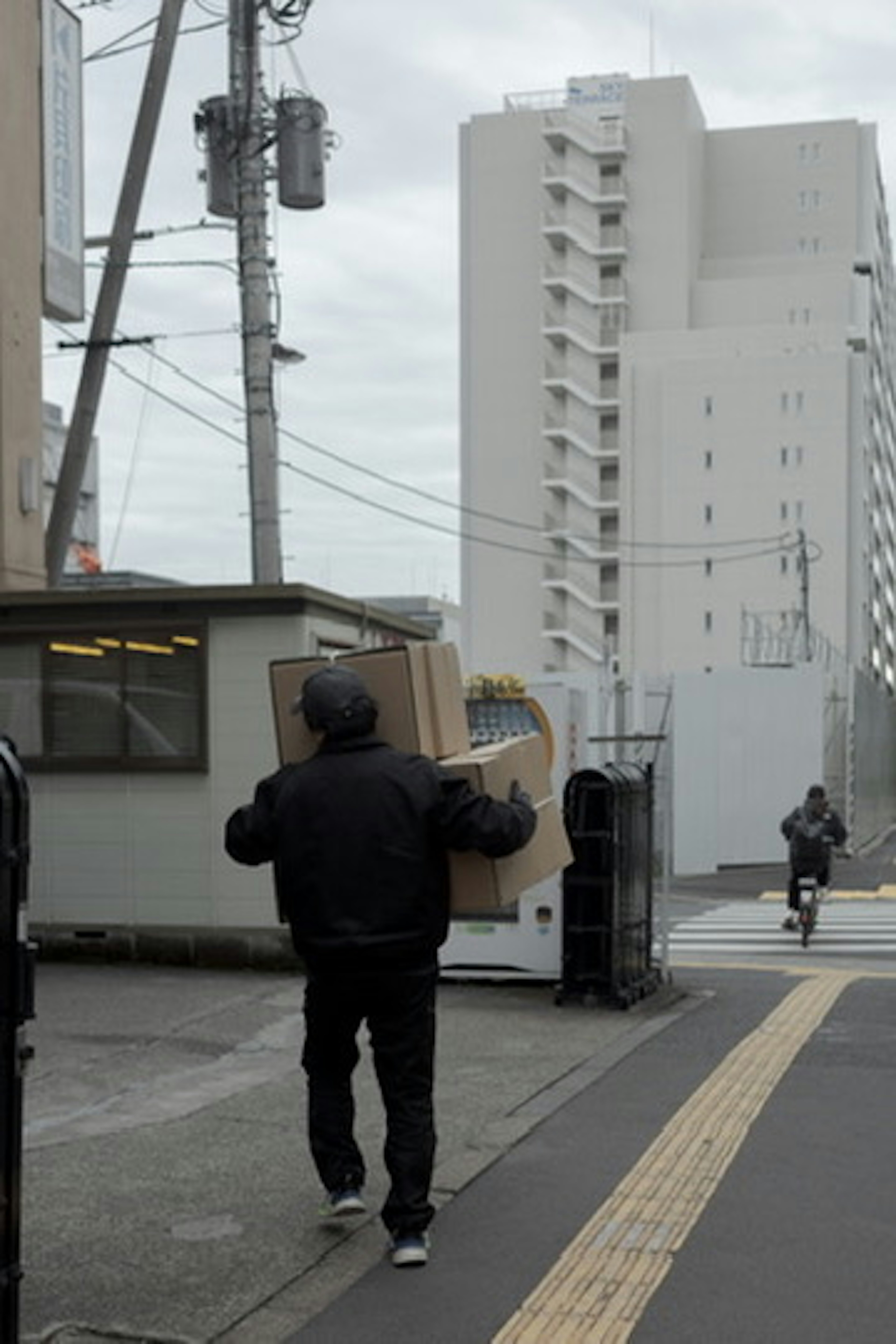 配送業者が大きな箱を運びながら街を歩く風景