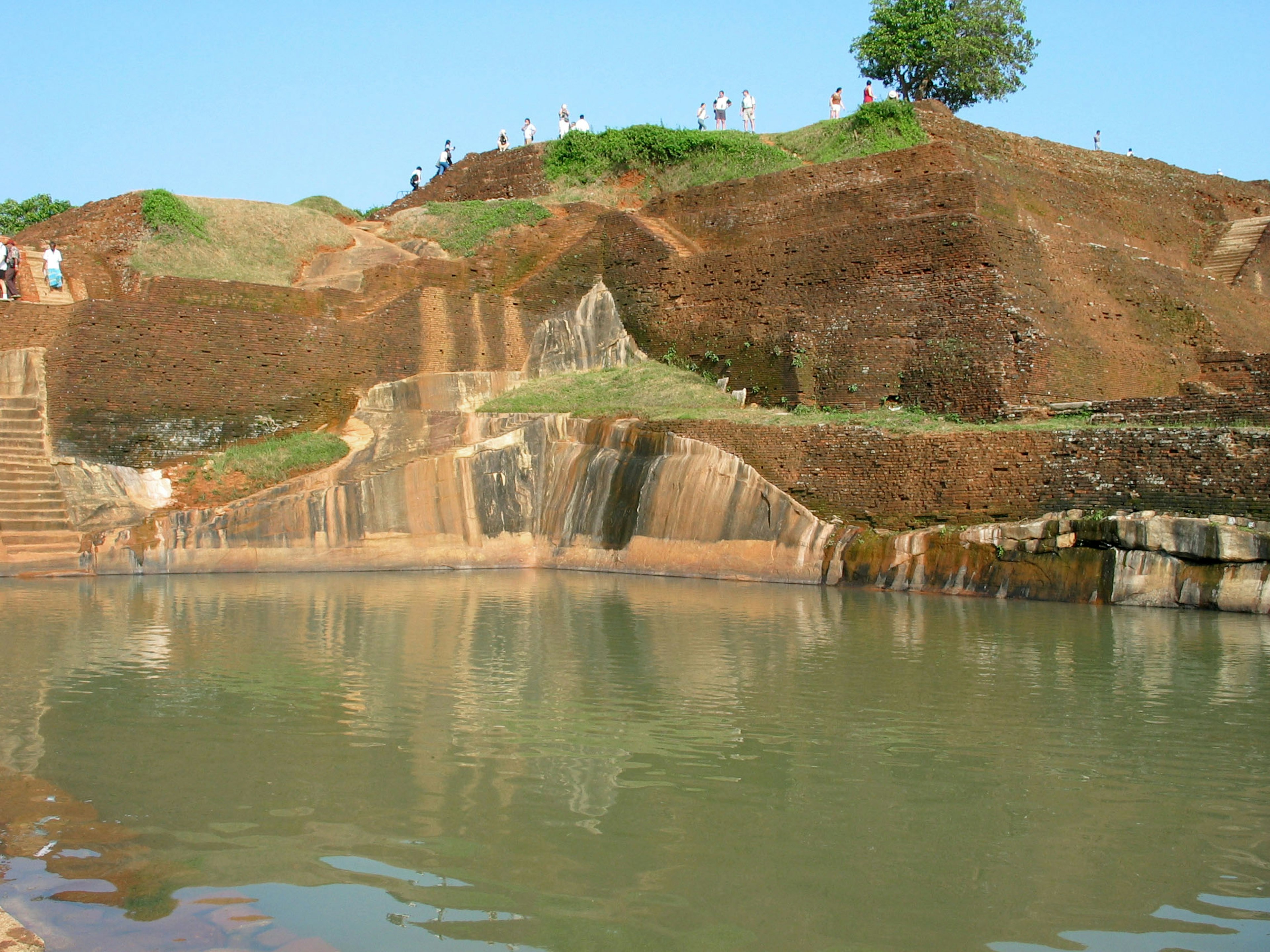 Calm water surface with a cliff and green trees in the background