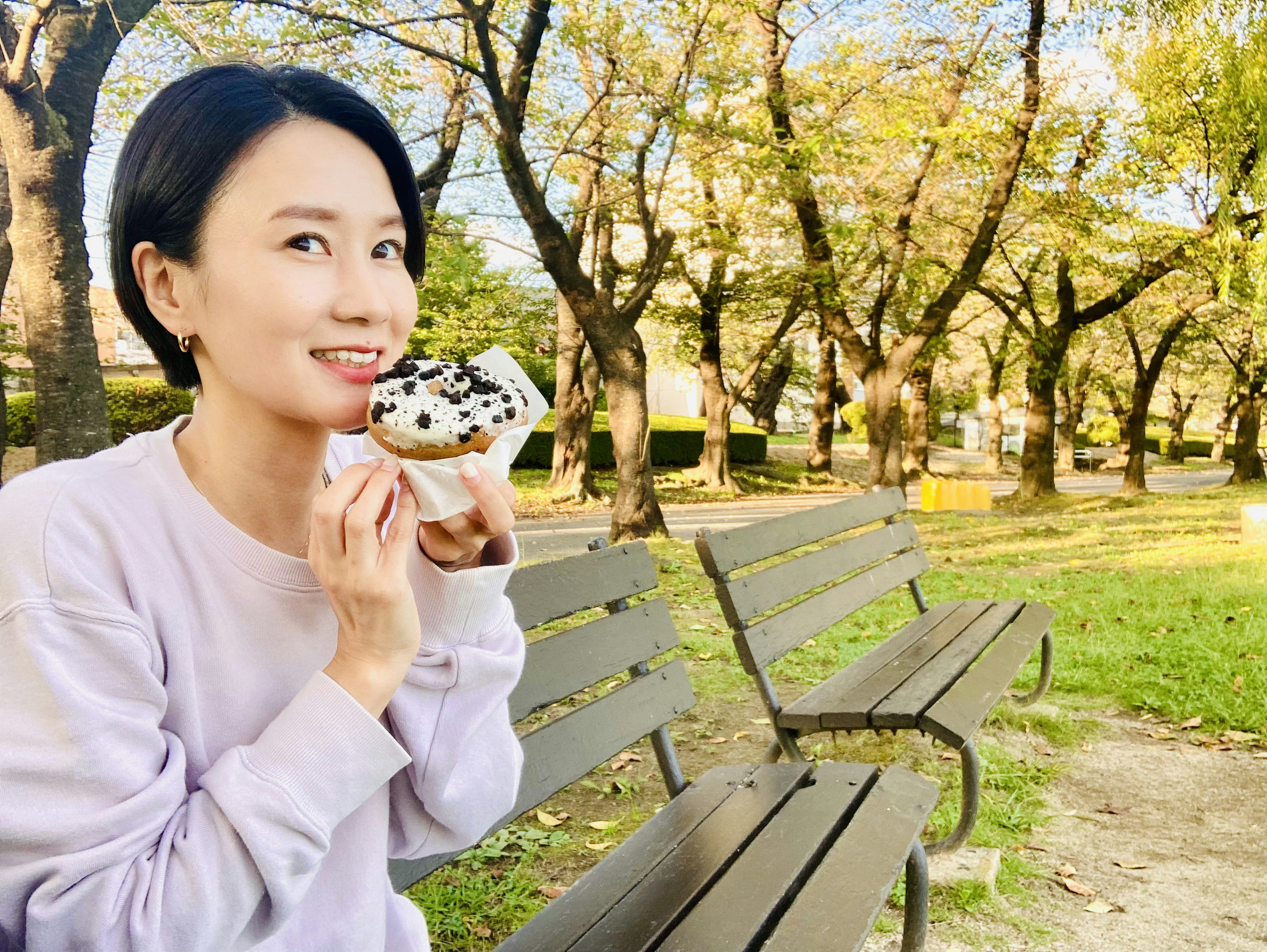 公園でスイーツを楽しむ女性の笑顔と秋の景色