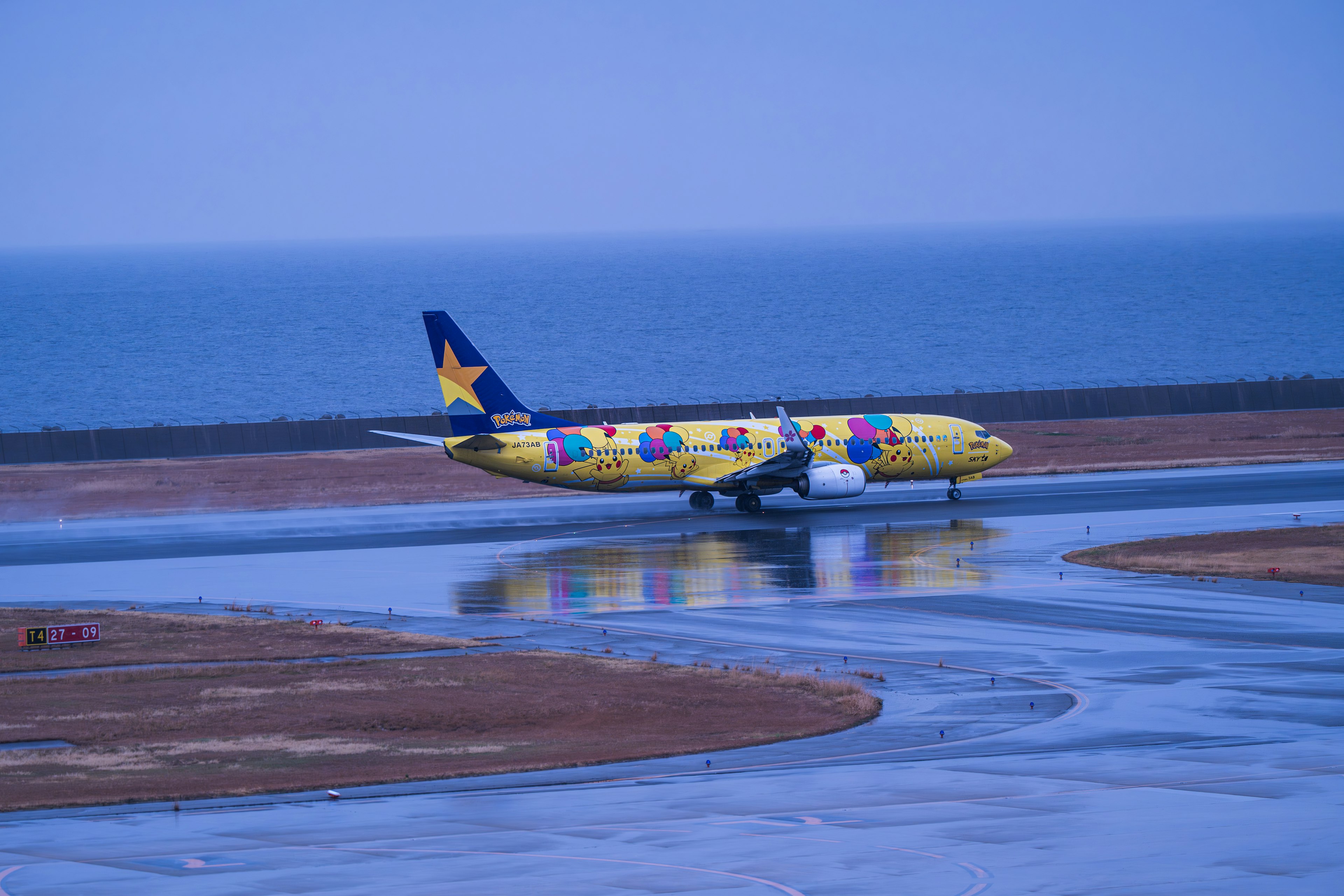 Colorful airplane taxiing on runway near the ocean