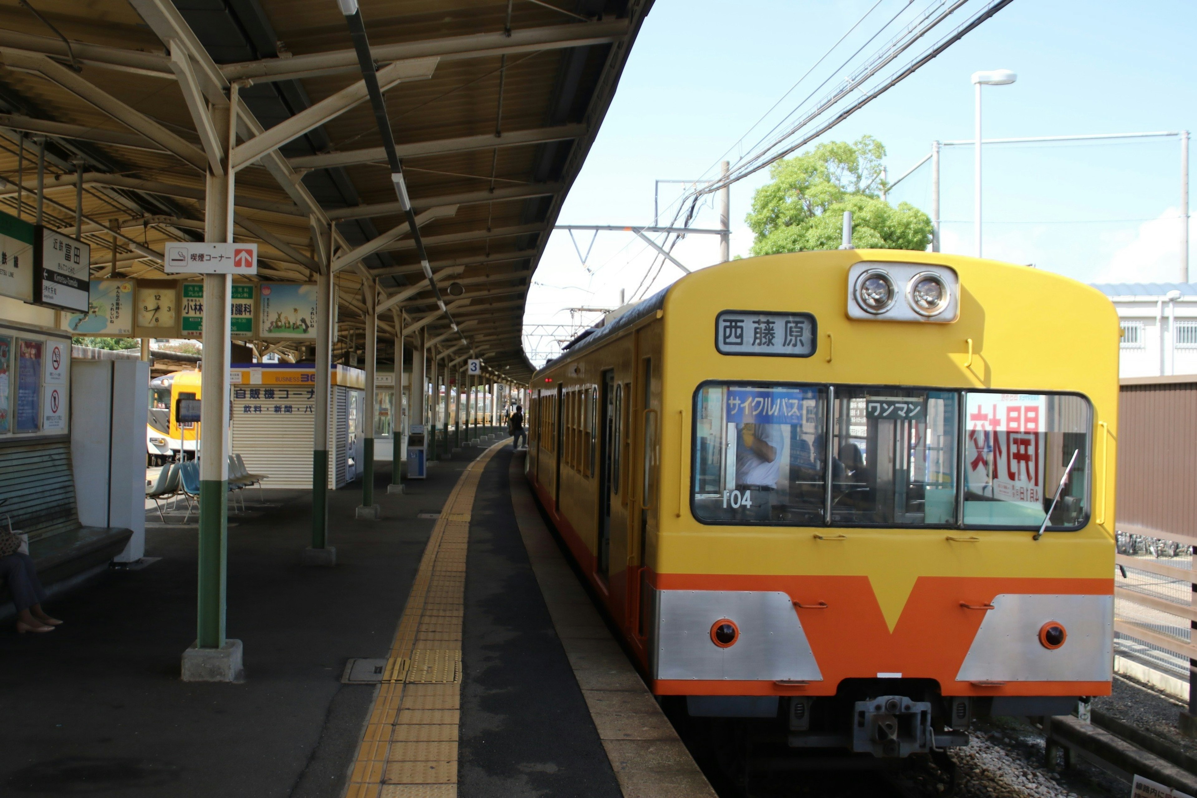 Yellow train at the station platform with green trees in the background