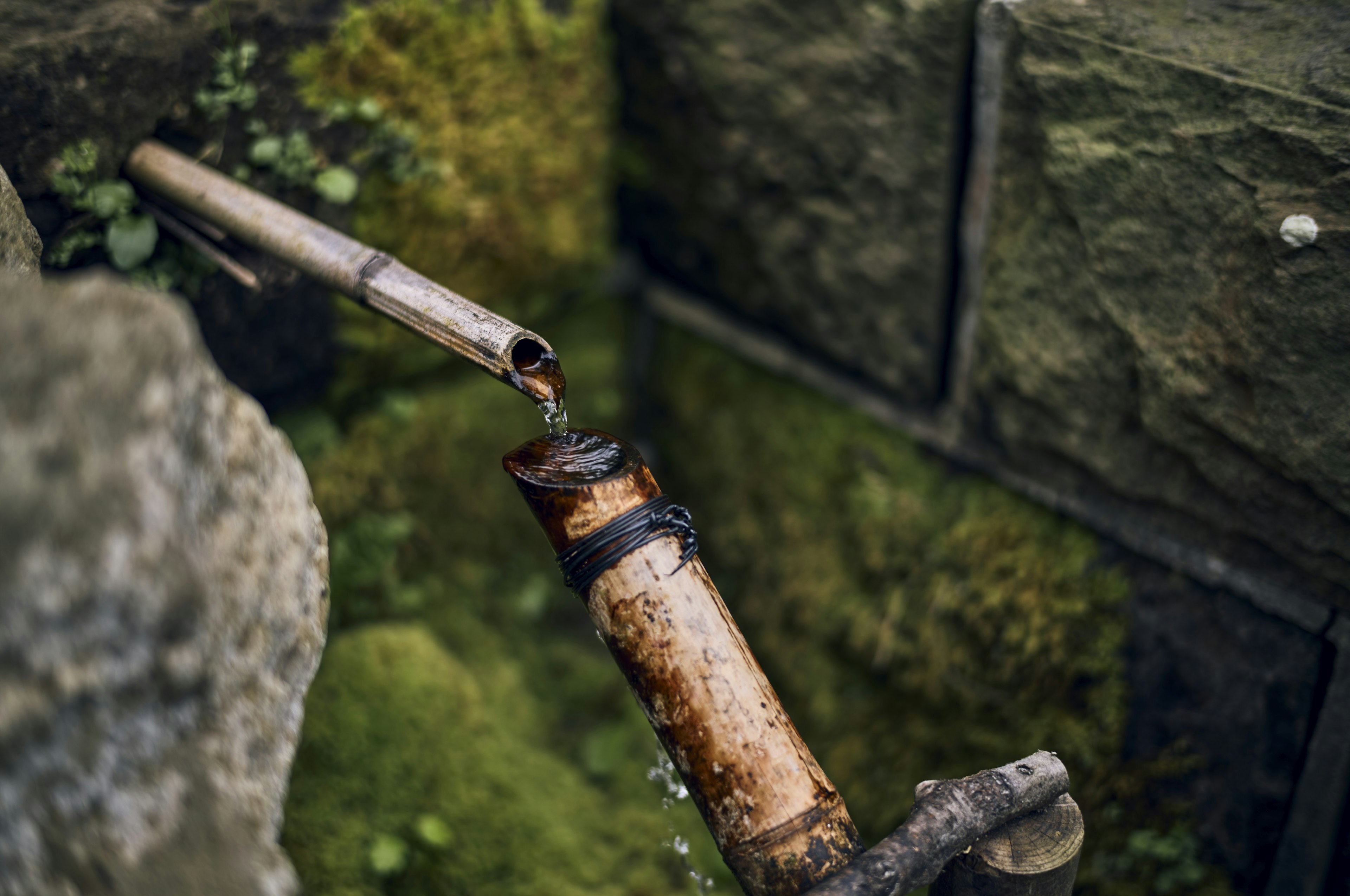 Alter Wasserrohr mit fließendem Wasser in der Nähe einer Steinmauer