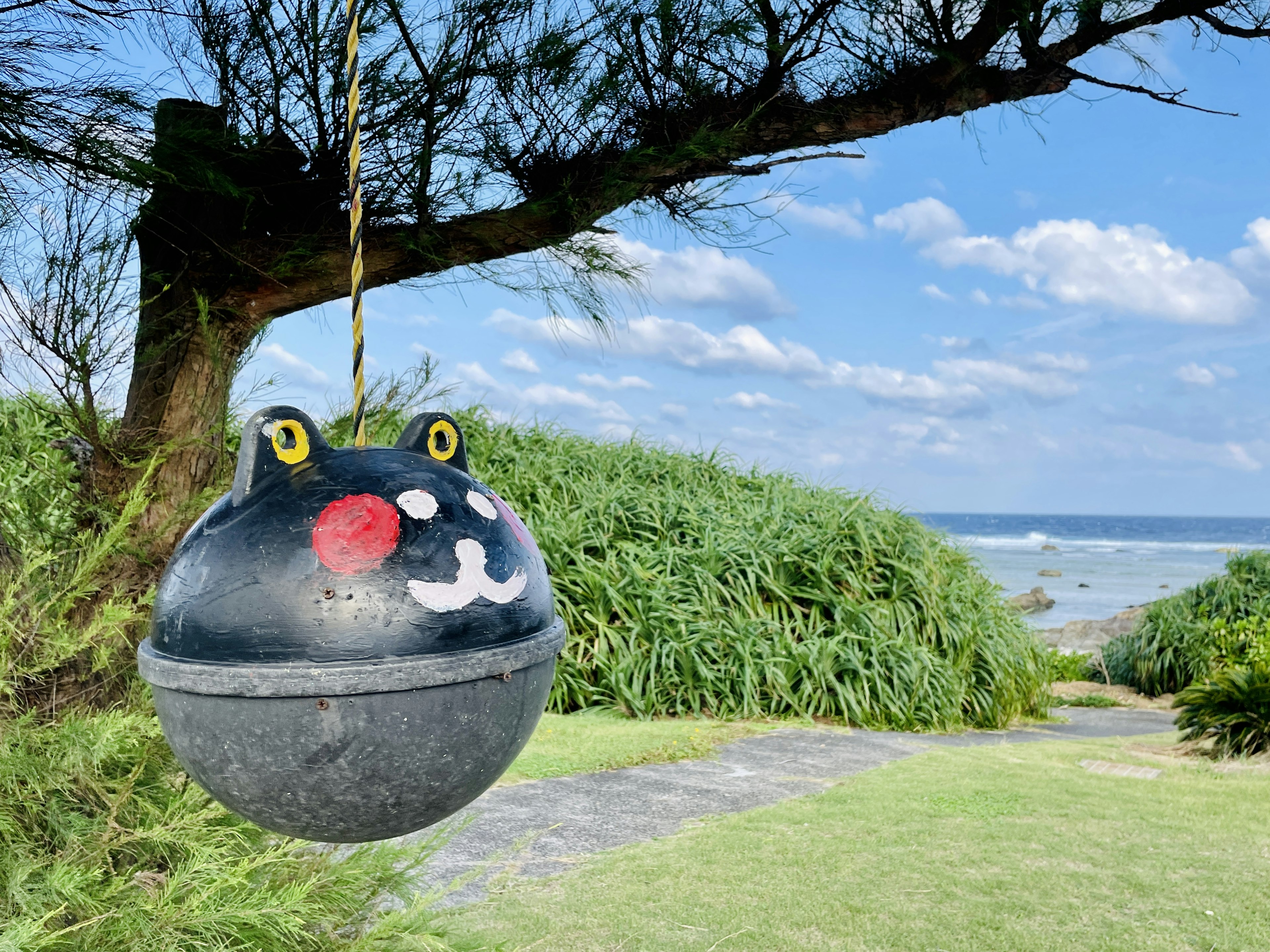 Colorful float decoration with a smiling cat face against a seaside background