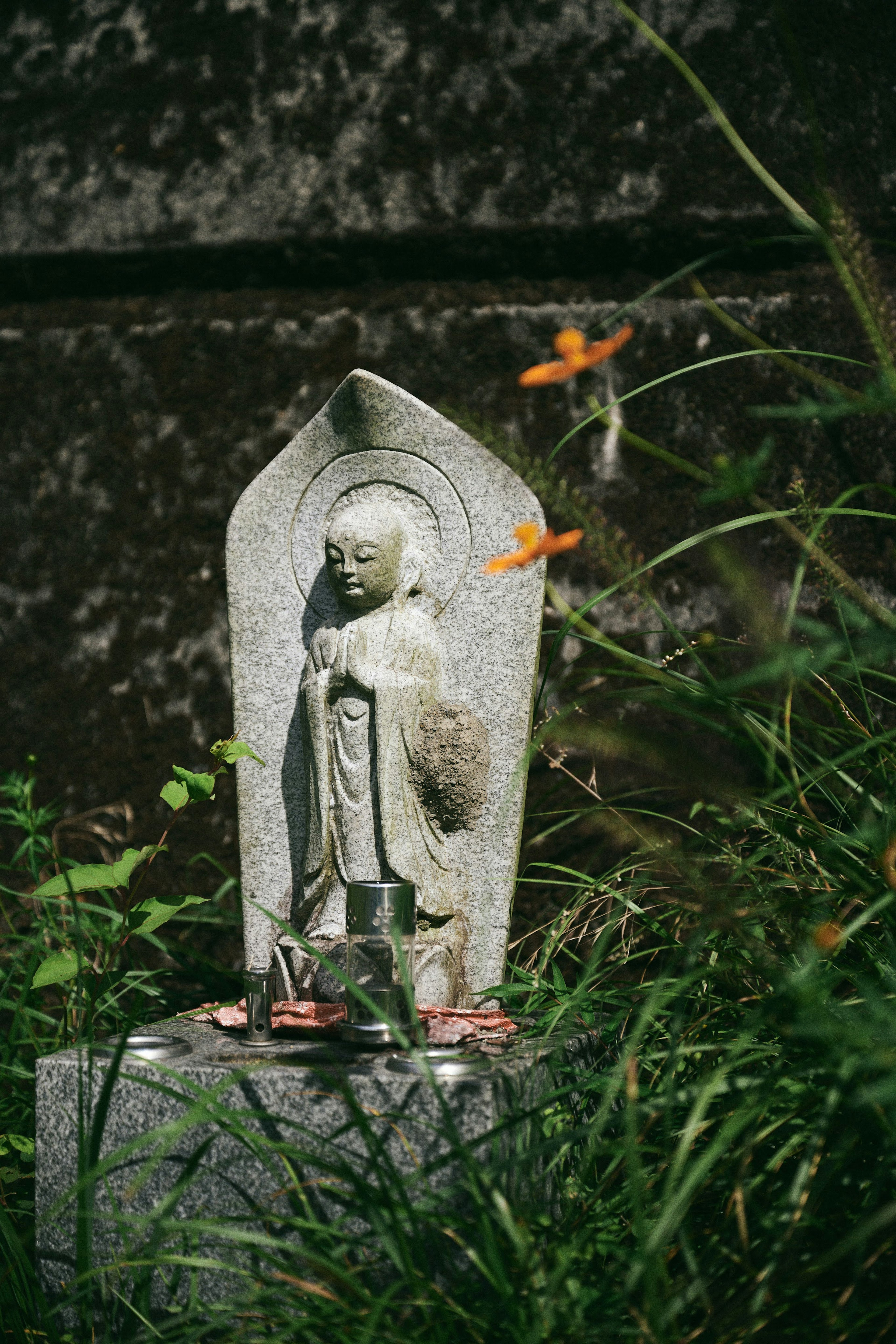 A stone statue of a Buddha surrounded by green grass