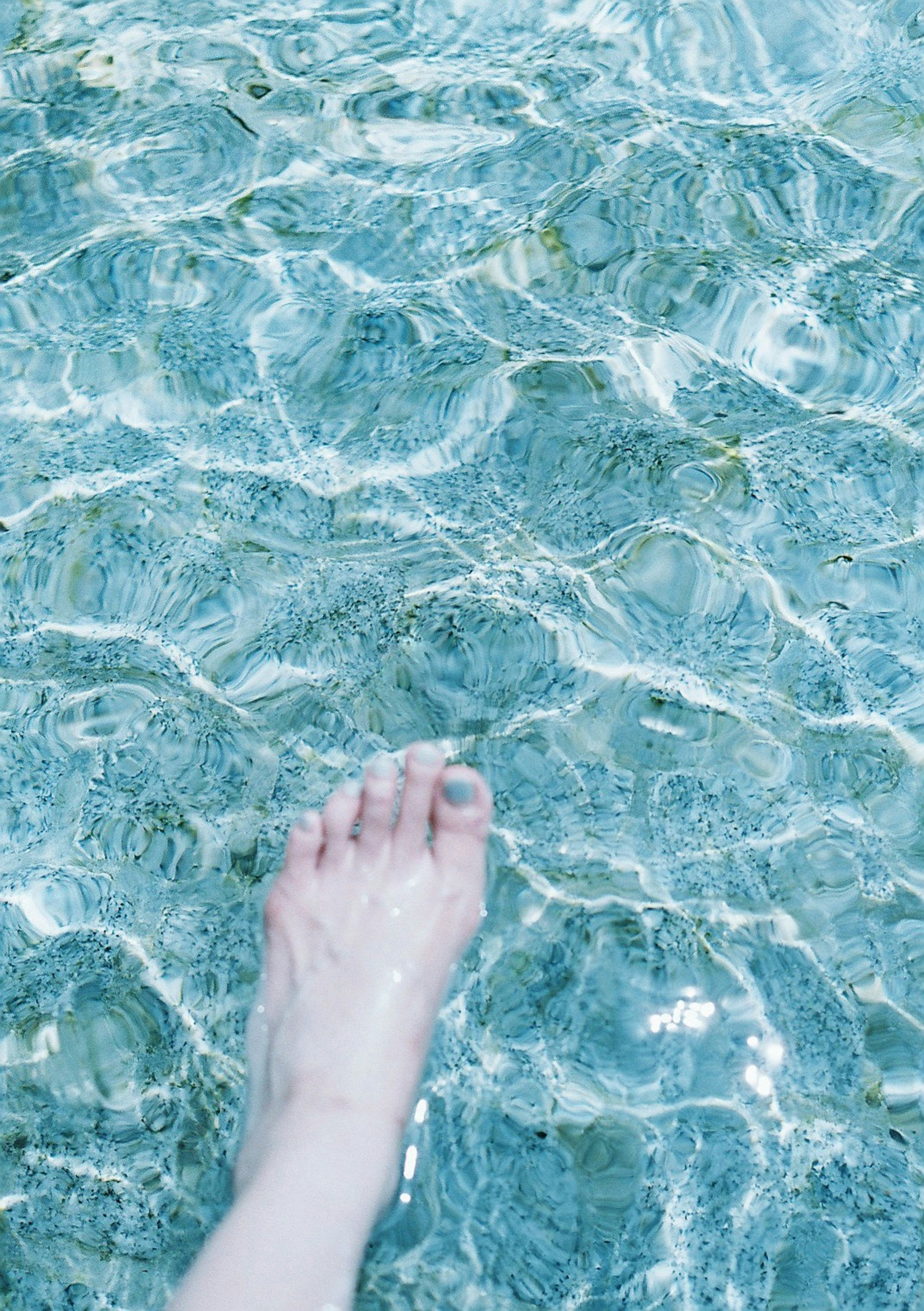 A foot submerged in clear water with ripples