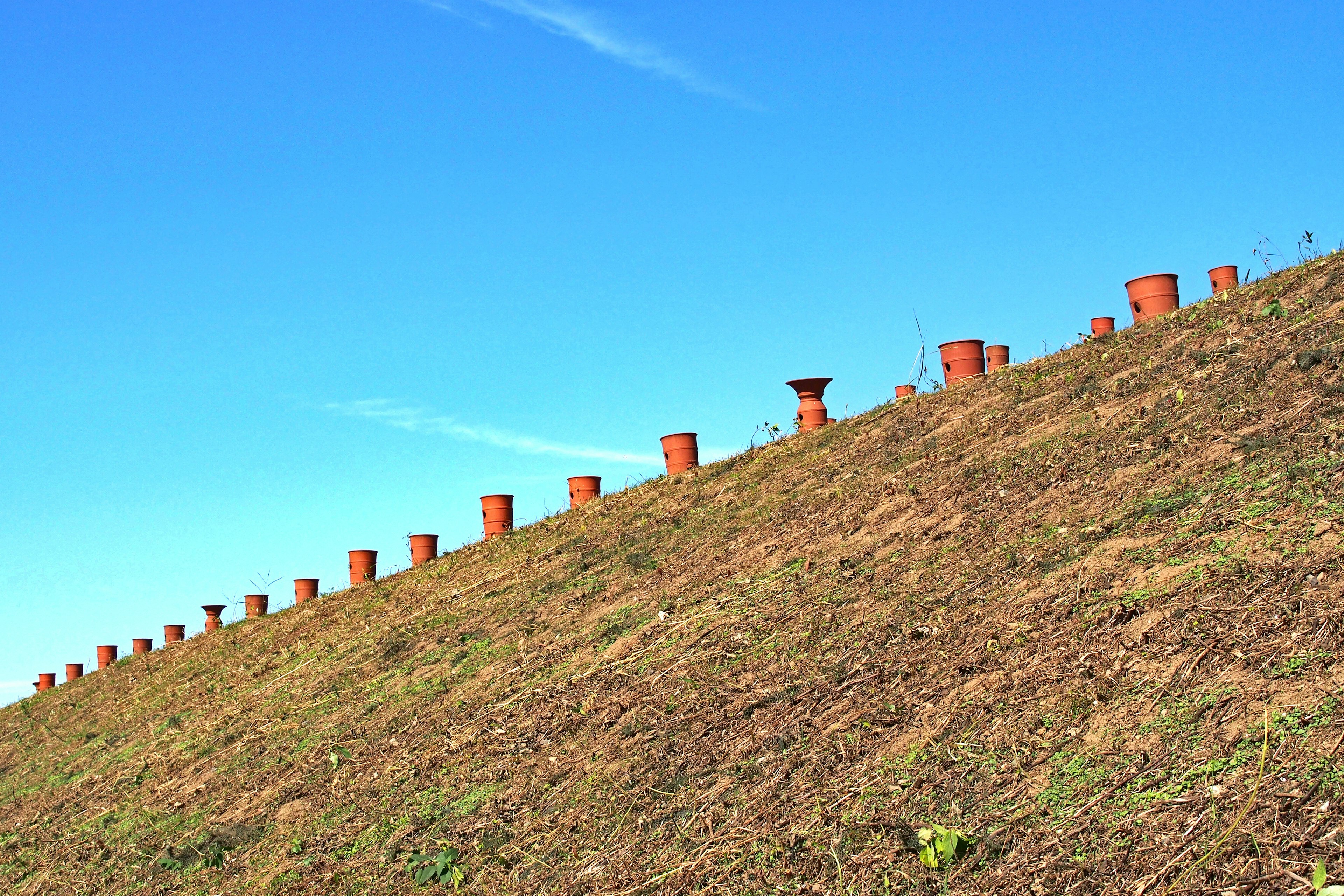 Ceramic pots arranged on a sloped hill under a blue sky