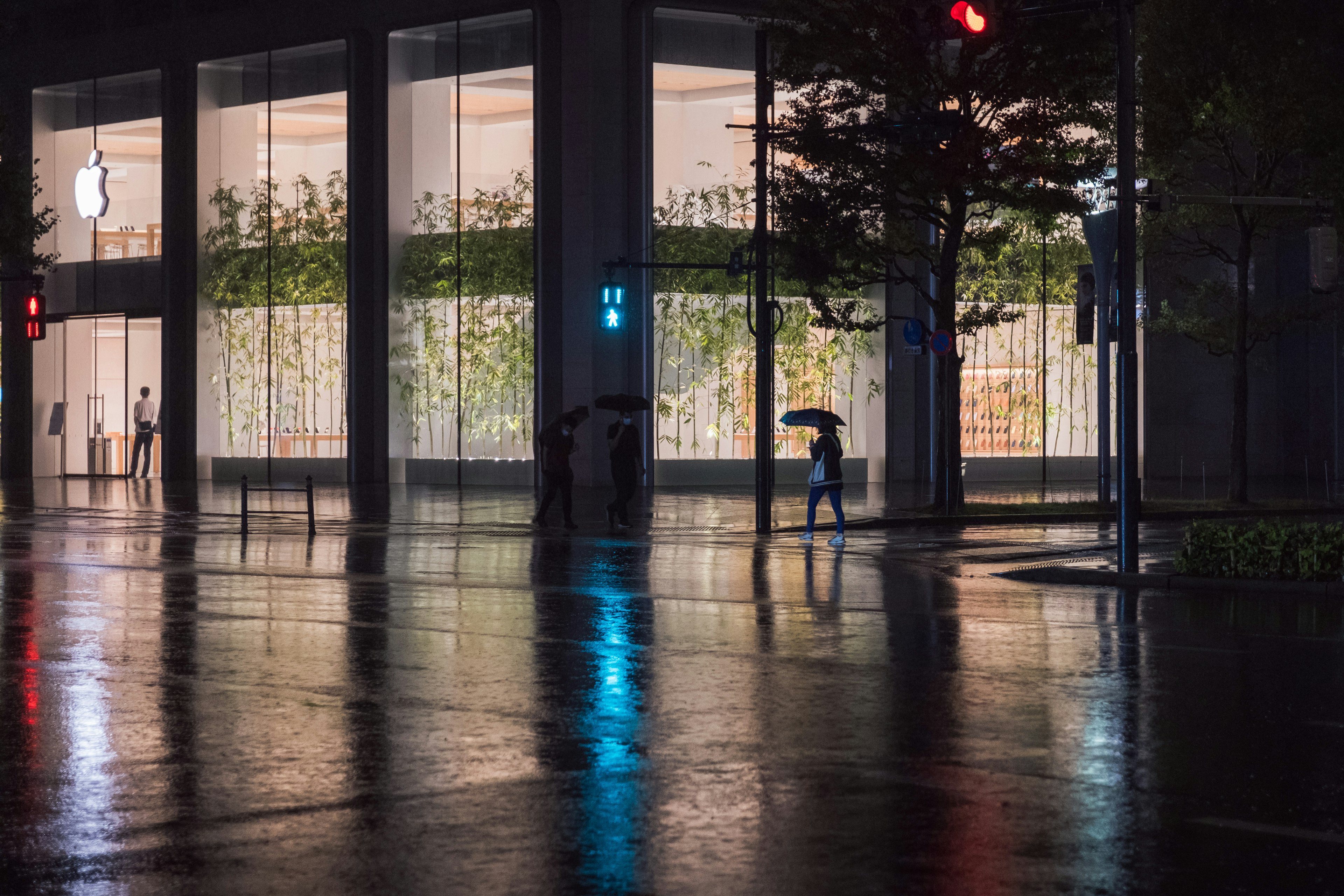 Eksterior Apple Store di malam hari dengan refleksi hujan