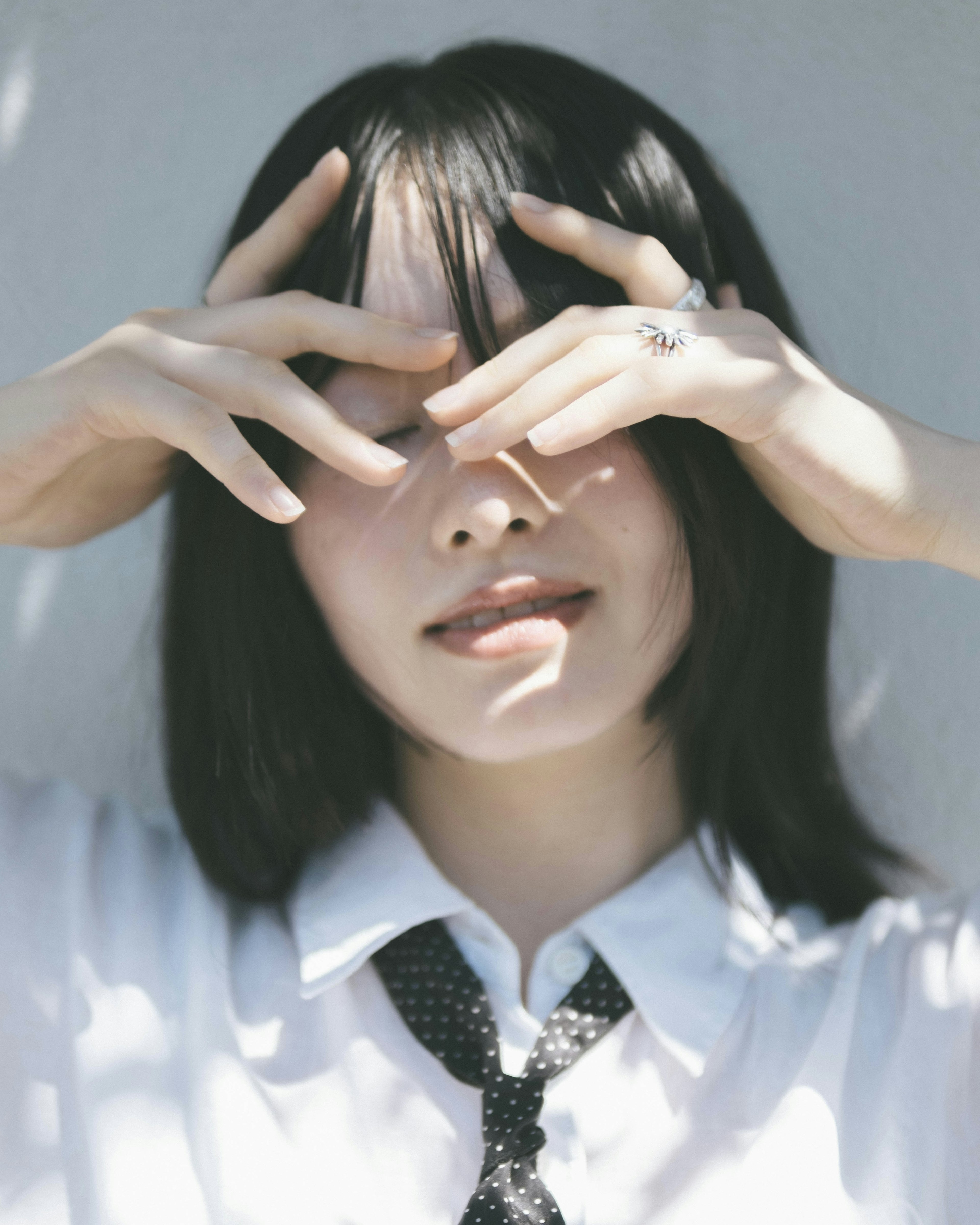 Young woman covering her face with hands wearing a white shirt and tie