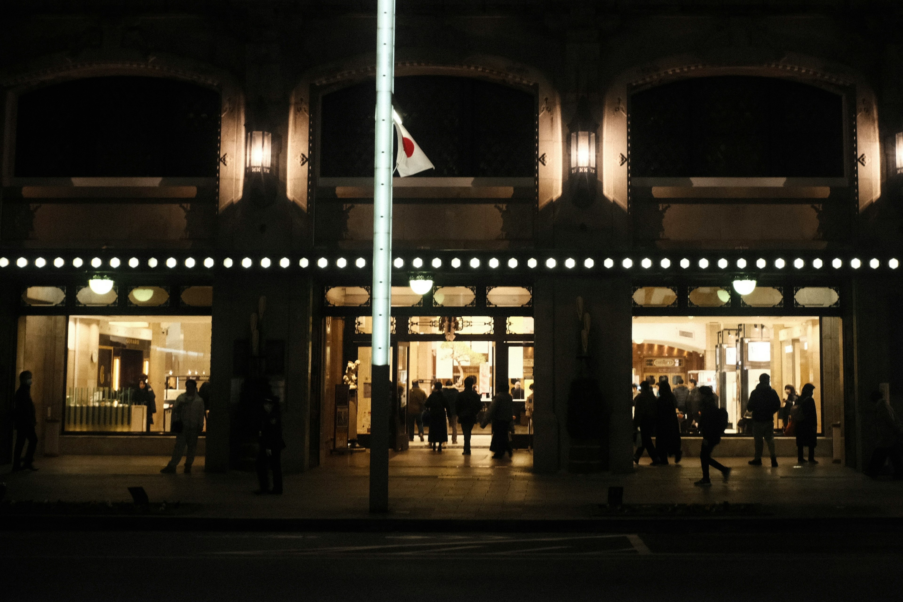 People standing in front of a brightly lit storefront at night