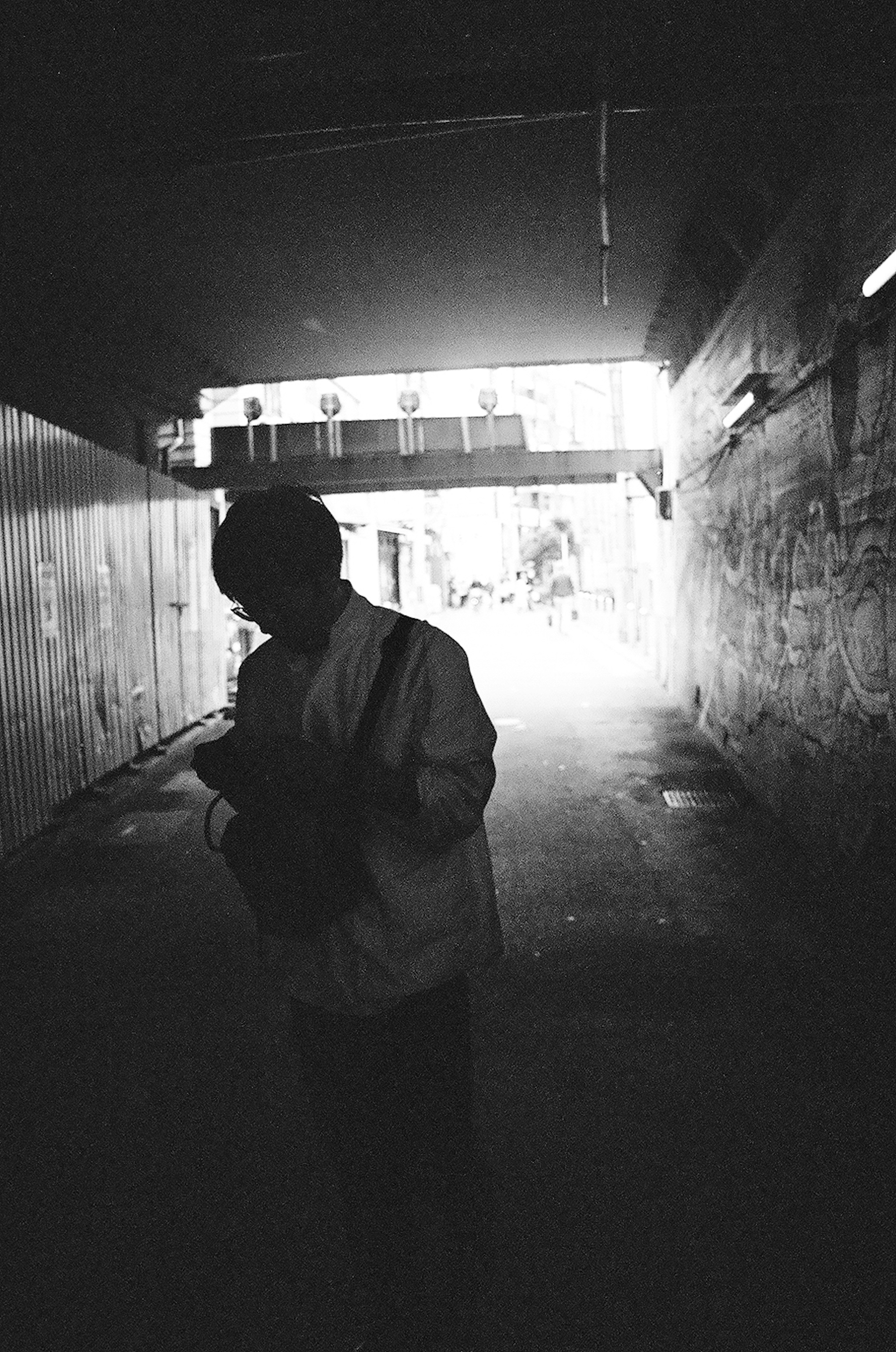 Silhouette of a person standing in a dark tunnel with light streaming in from behind