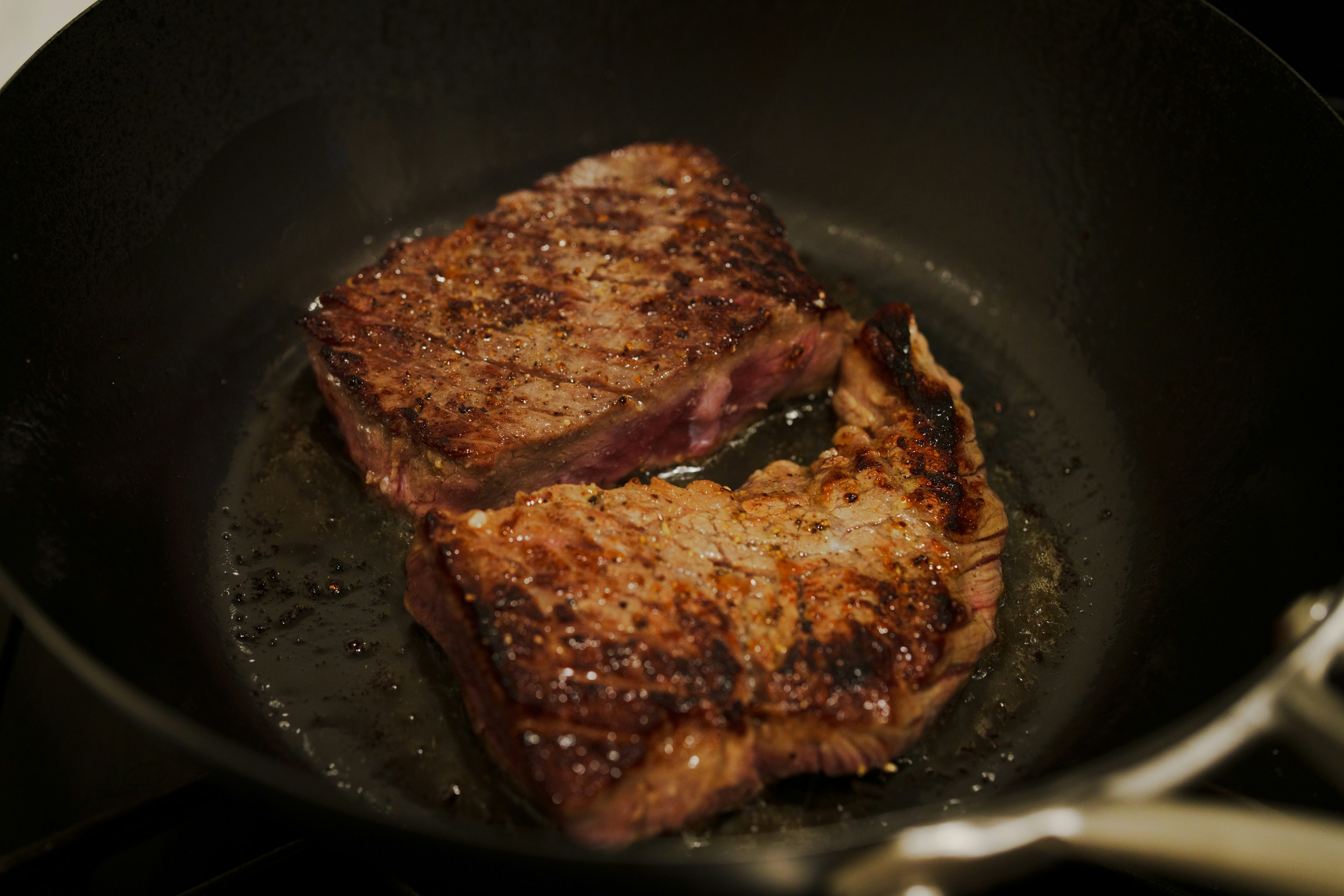 Two juicy steaks sizzling in a frying pan